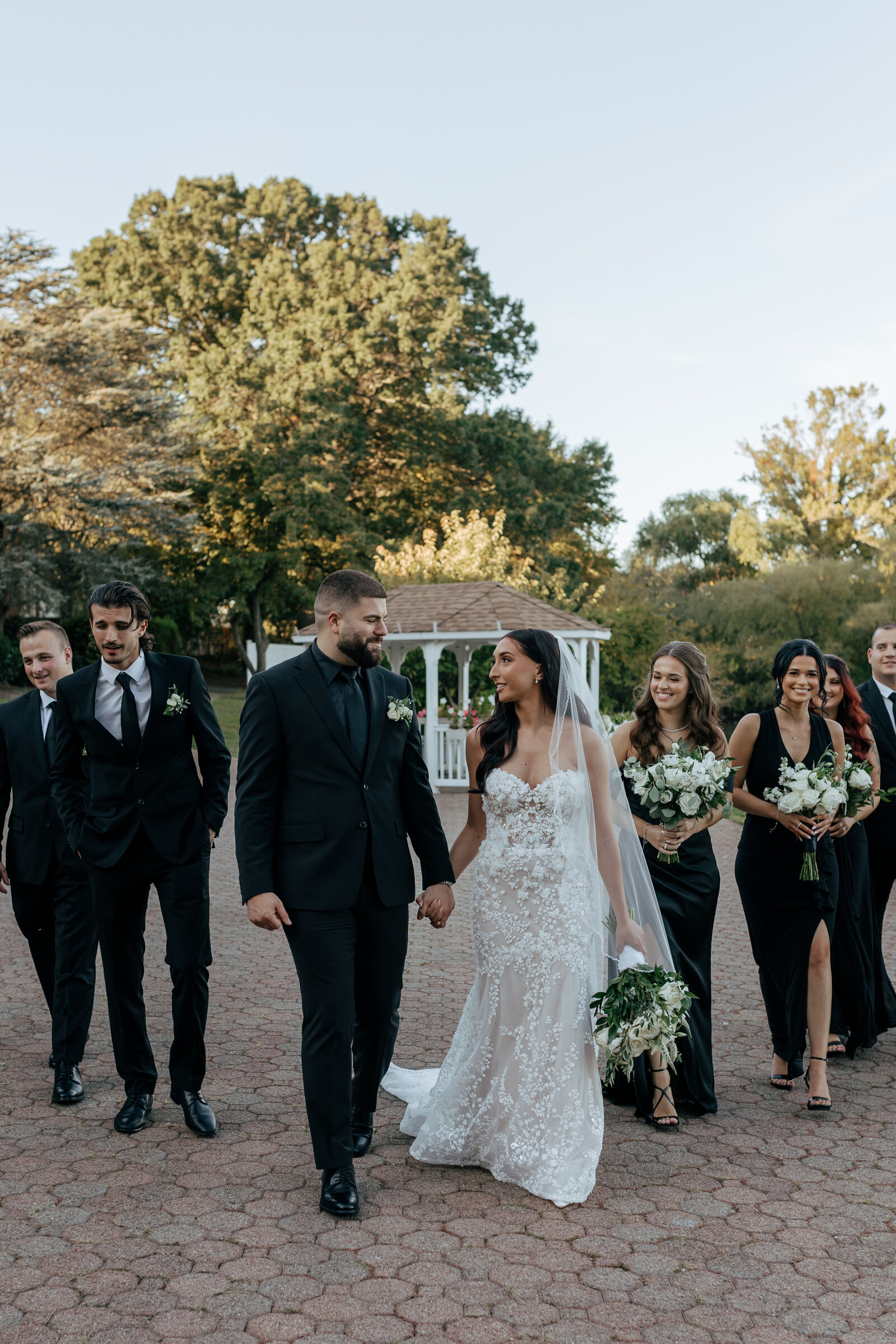 Groom and bride along with their wedding party taking documentary-style photos in the courtyard located in Long Island, NY