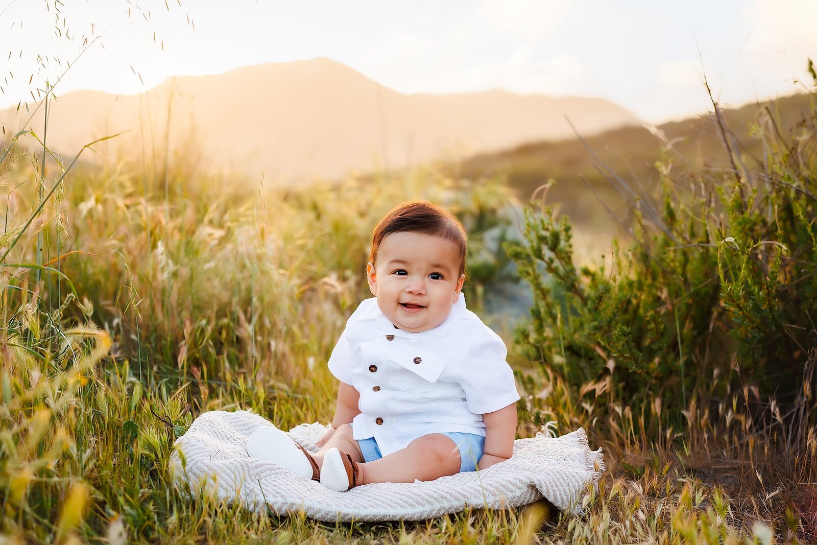 Baby boy sitting on a blanket in a field