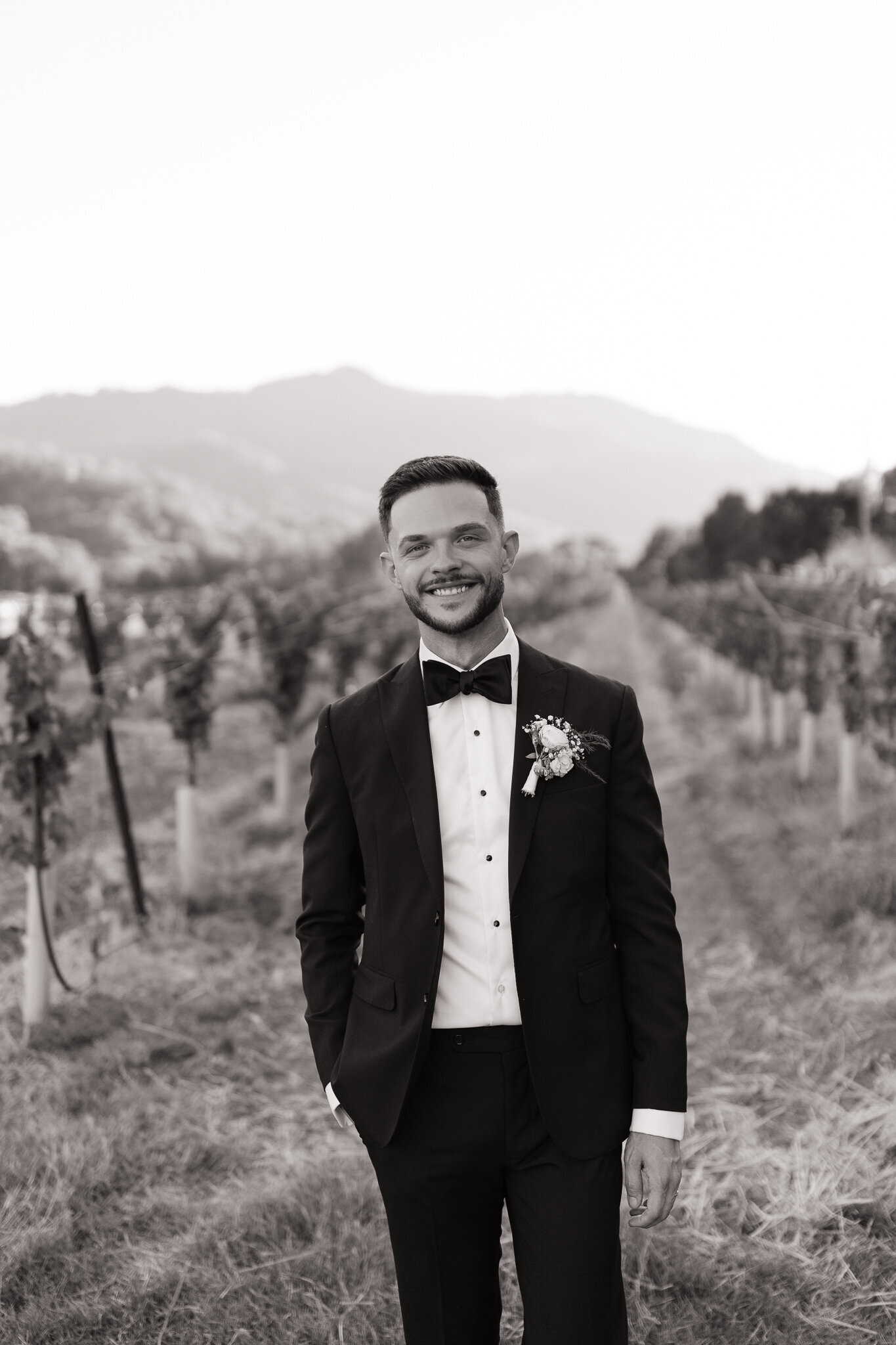 Groom poses for solo portraits with vineyard back drop Nelson Family Vineyards