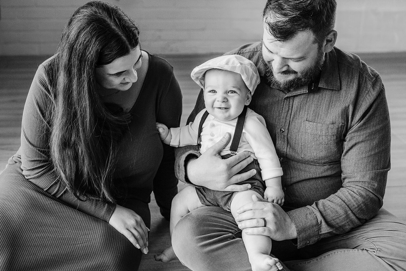 black and white image of parenting smiling with toddler boy wearing a cap