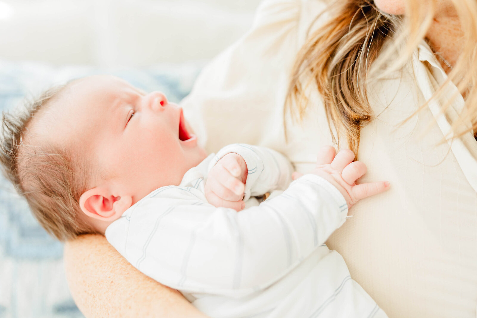 Newborn yawns in mom's arms