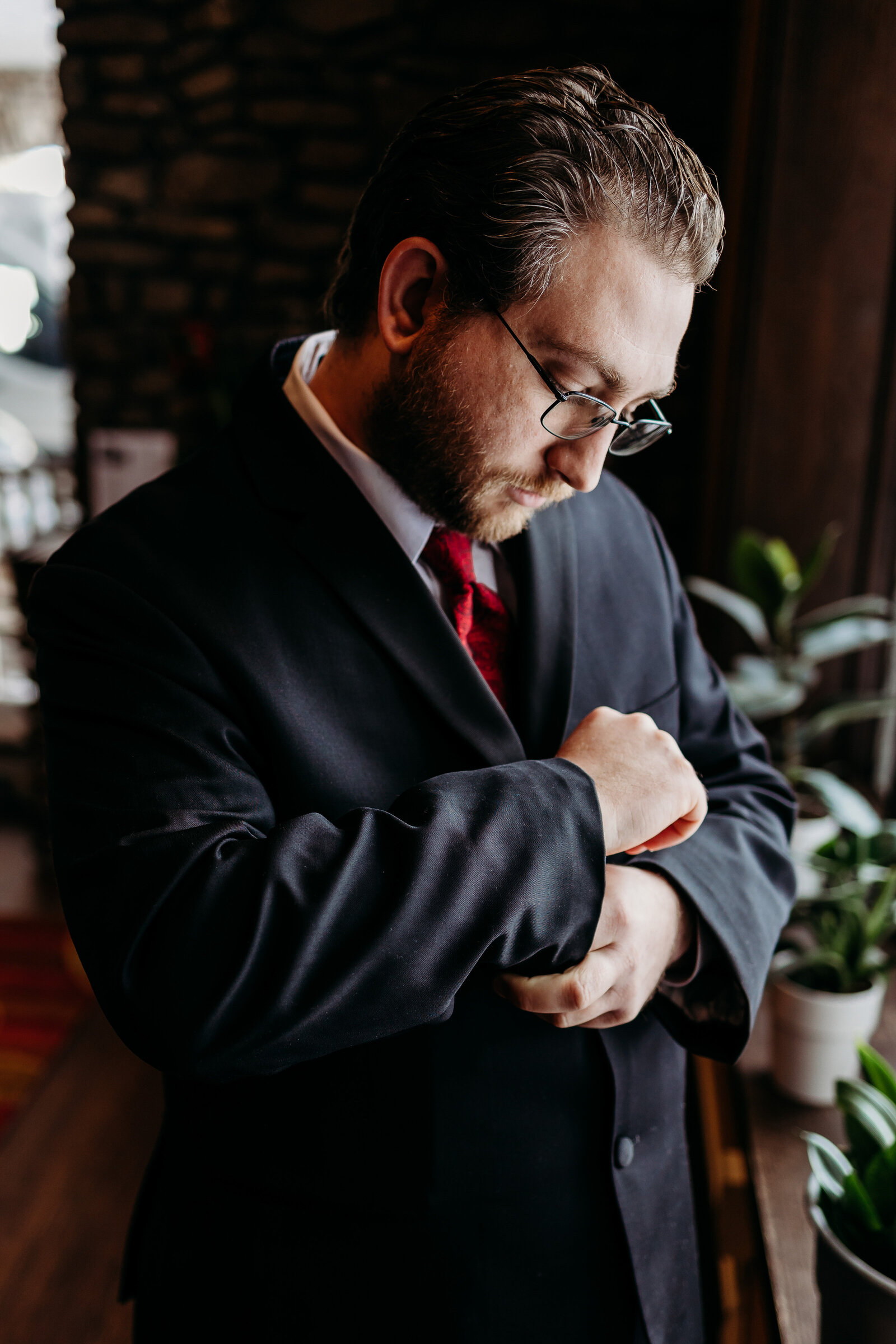 Groom fixes cuff of his jacket while getting ready for his wedding day