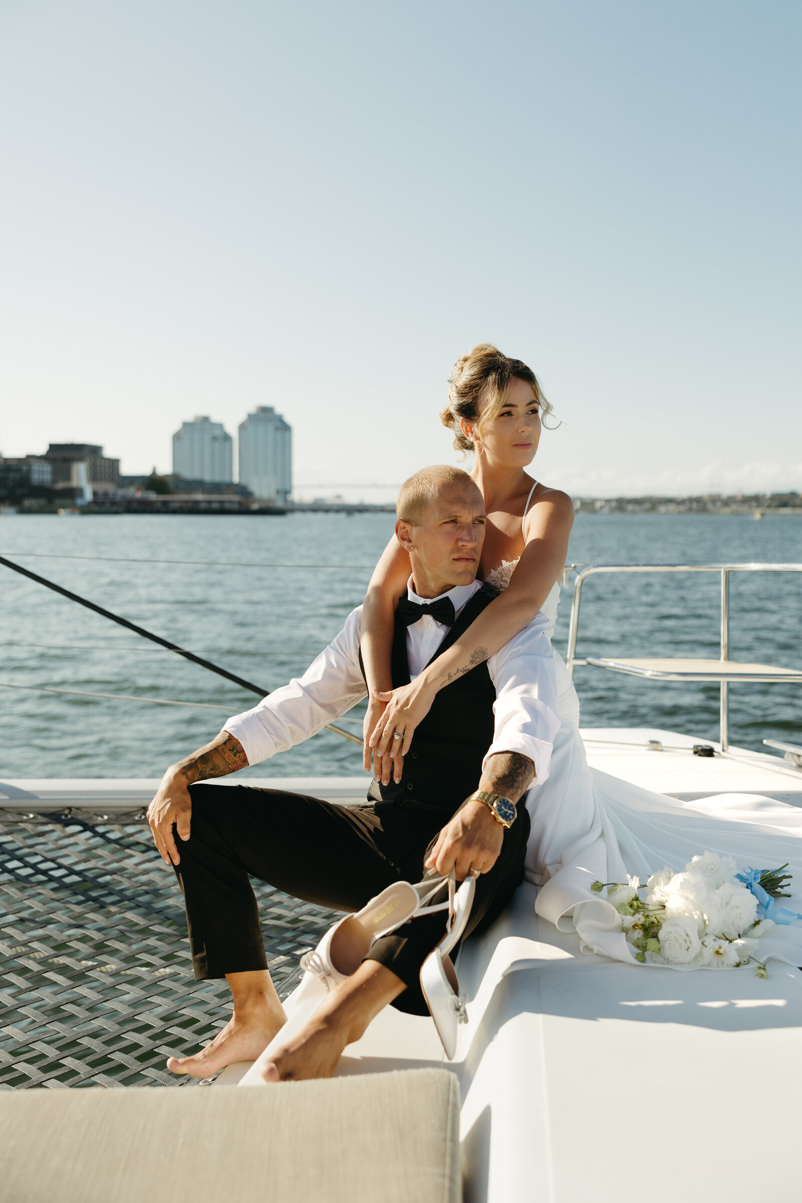 A couple poses for bridal portraits on the deck of the Reverie in the Halifax harbour.