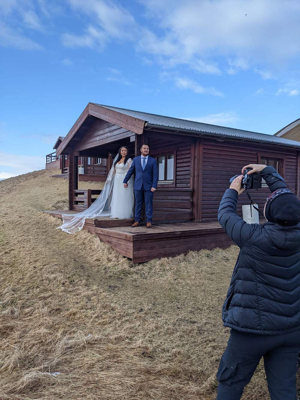 A Virginia wedding photographer takes photos of a couple during a first touch moment outside of their Airbnb cabin in Iceland.