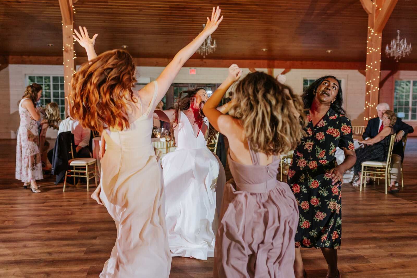 A group of women dance together at a barn wedding reception