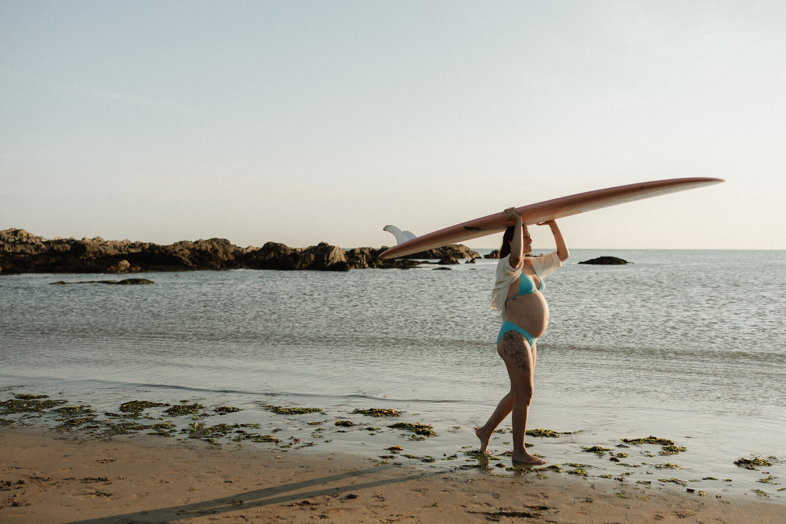 Portrait of pregnant woman carrying a surfboard in the sea