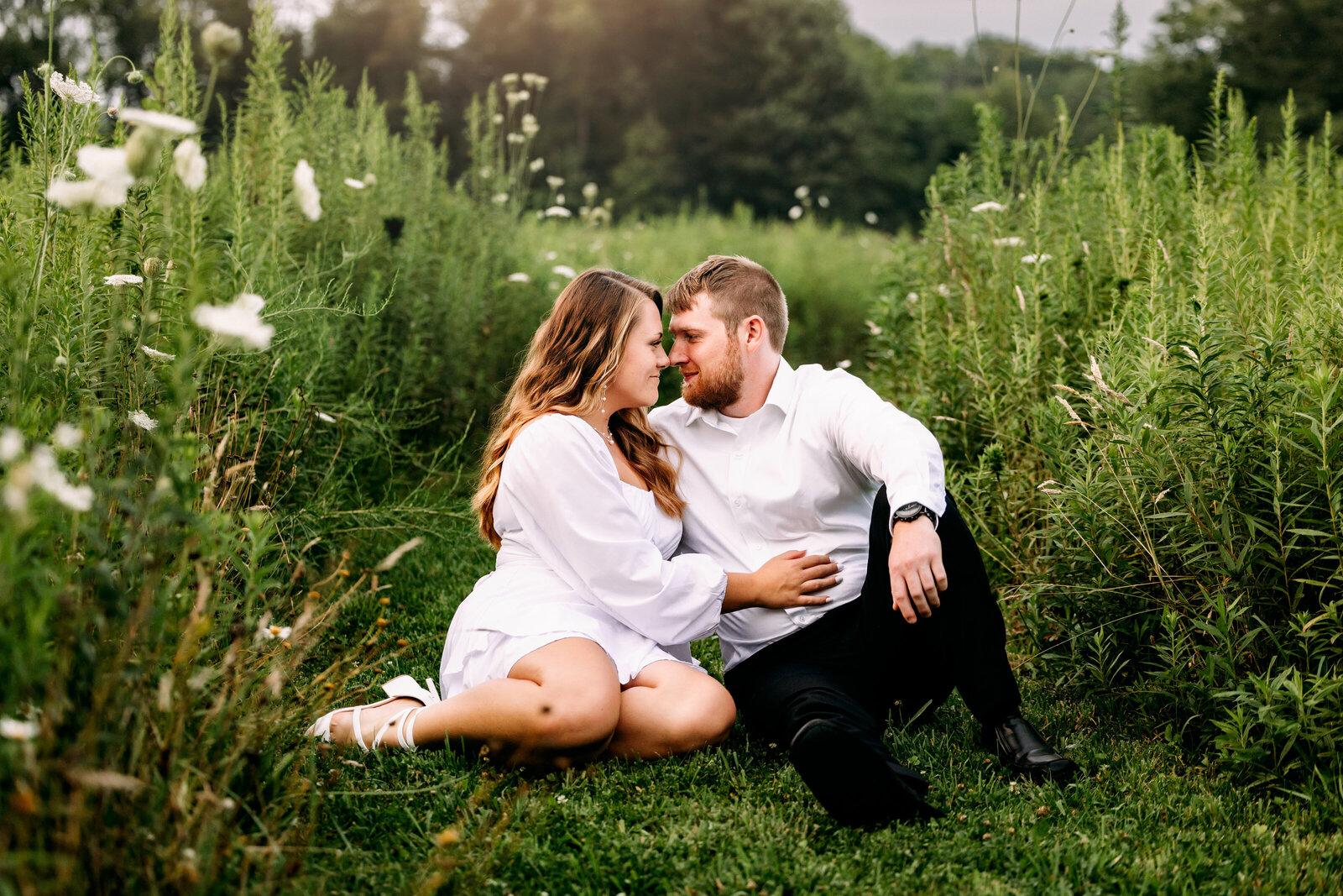 Couple snuggles up together in a field of tall grasses