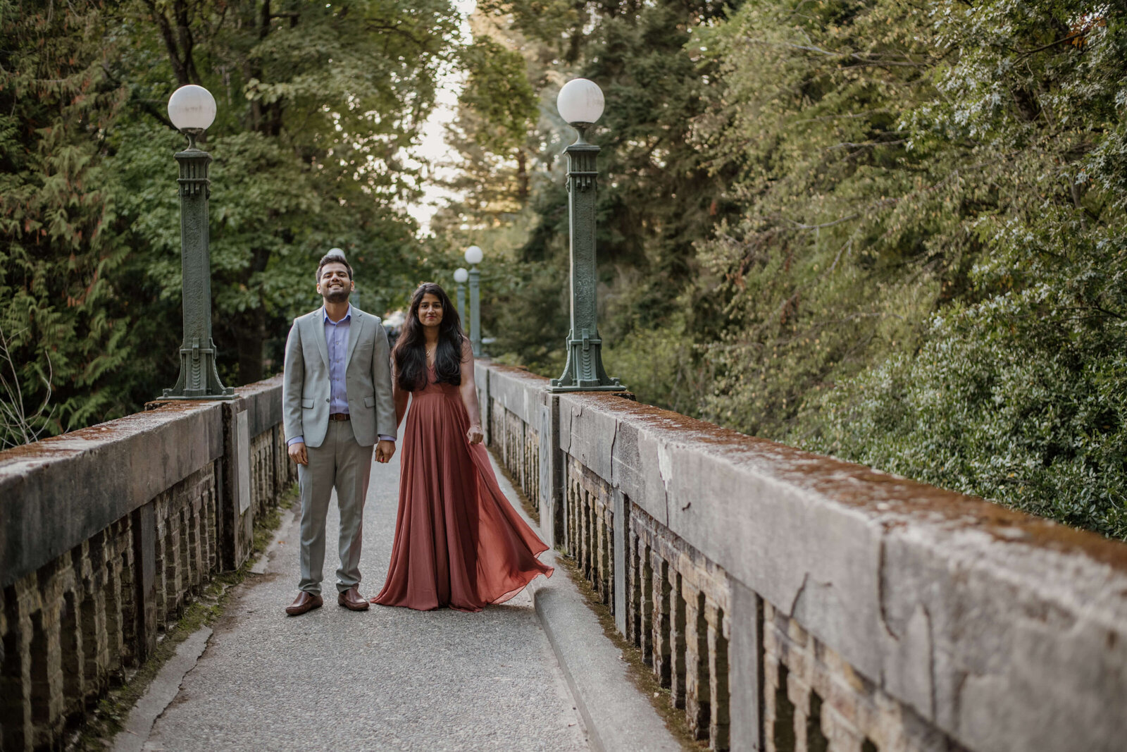 Couple standing on bridge together.
