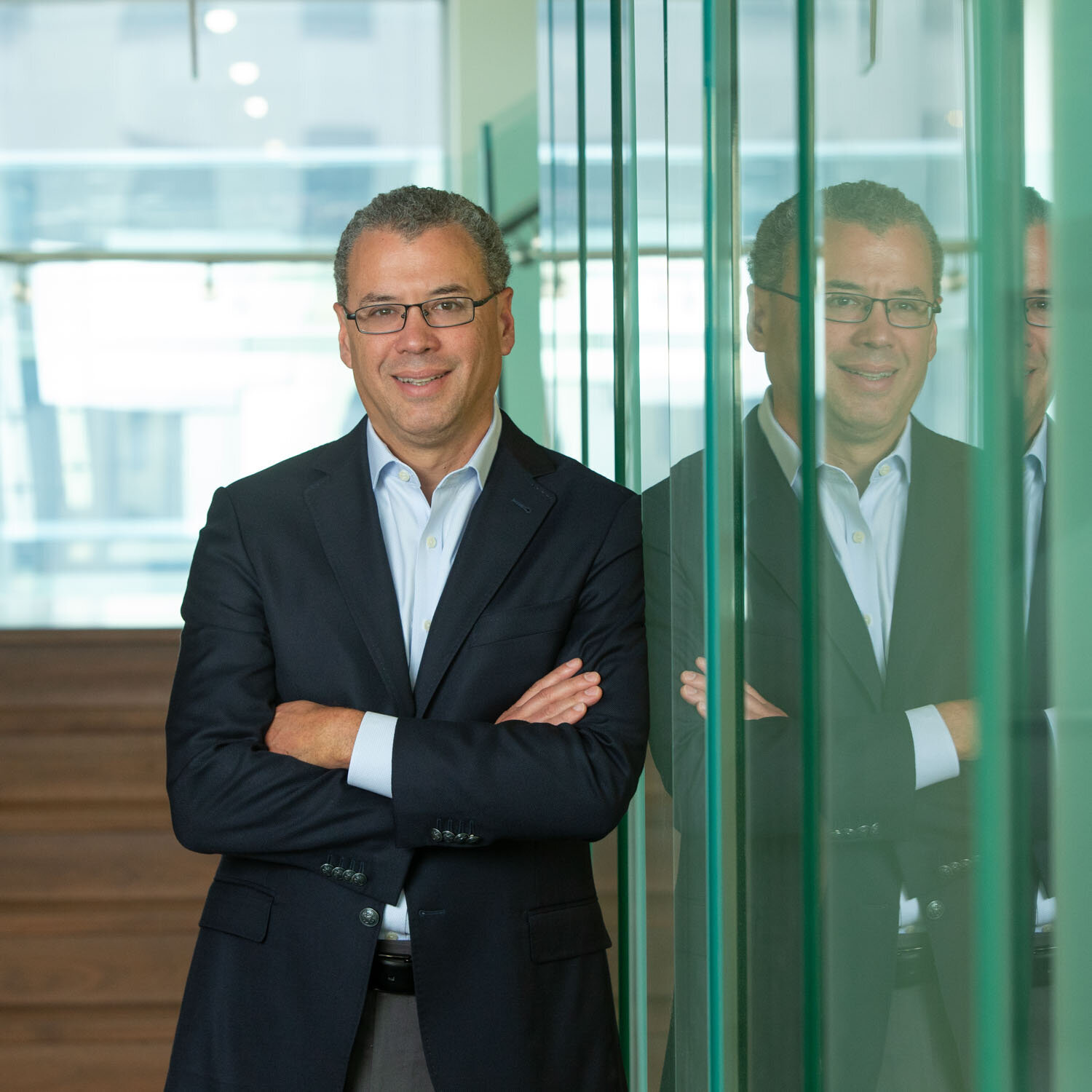 Man in a suit standing confidently beside a glass wall with reflection
