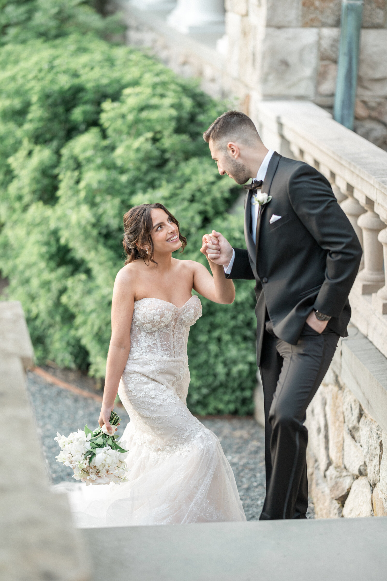 A groom leads his bride up the stairs of Blithewold Mansion