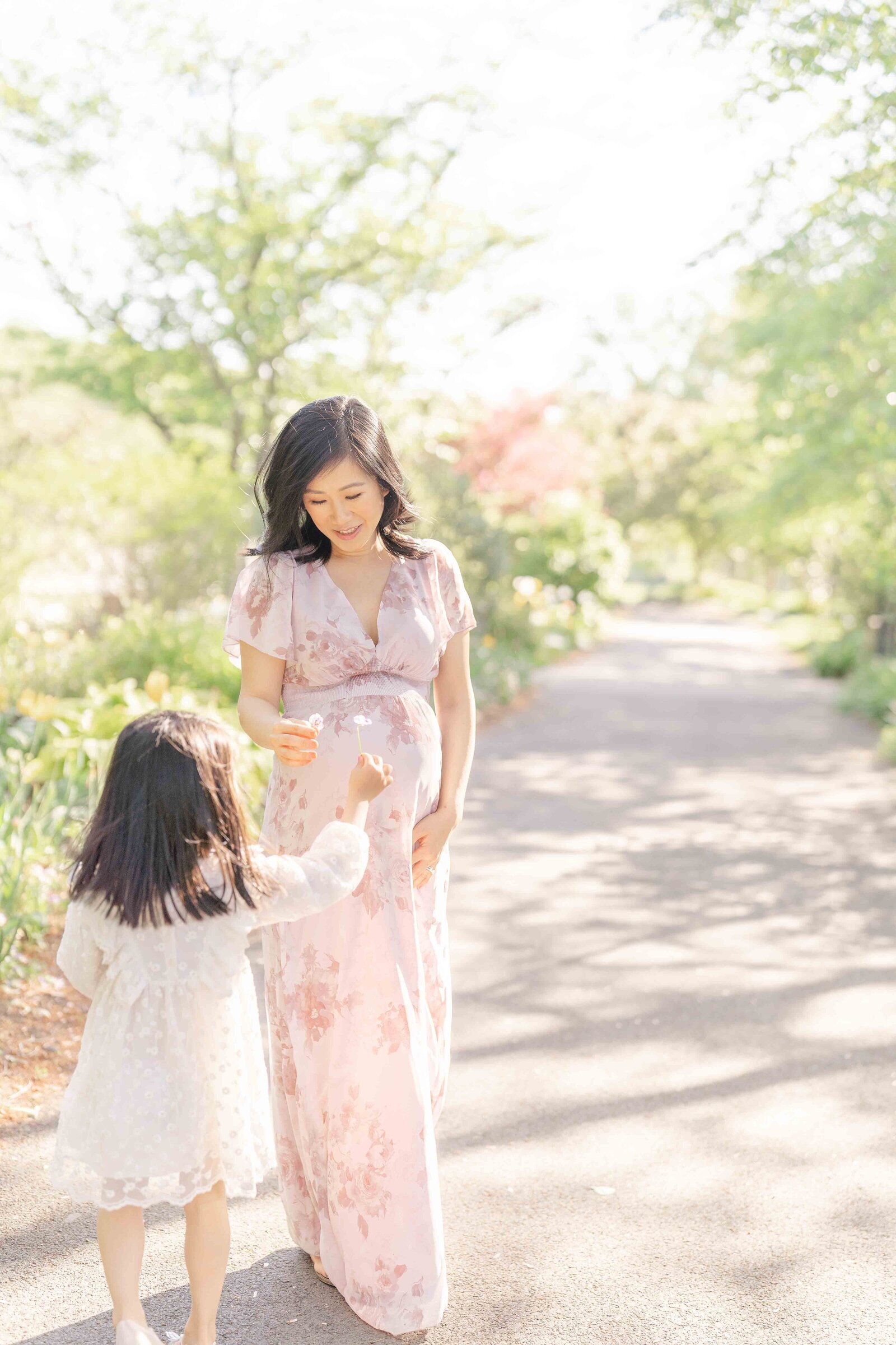 big sister gives mom flower during Ashburn, VA maternity photography