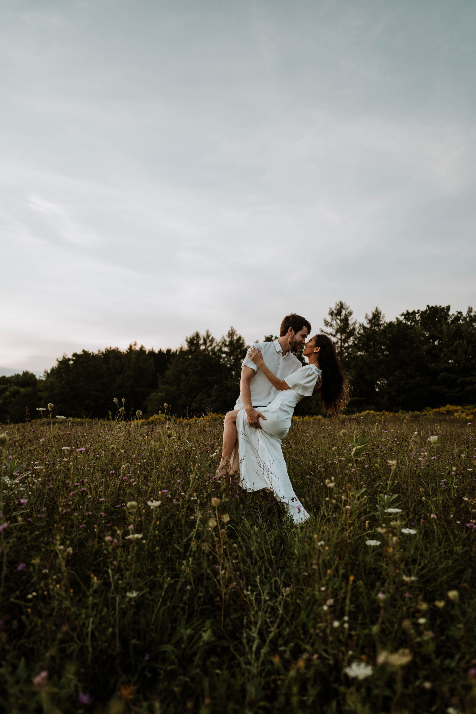 Newly eloped couple dancing in a field.