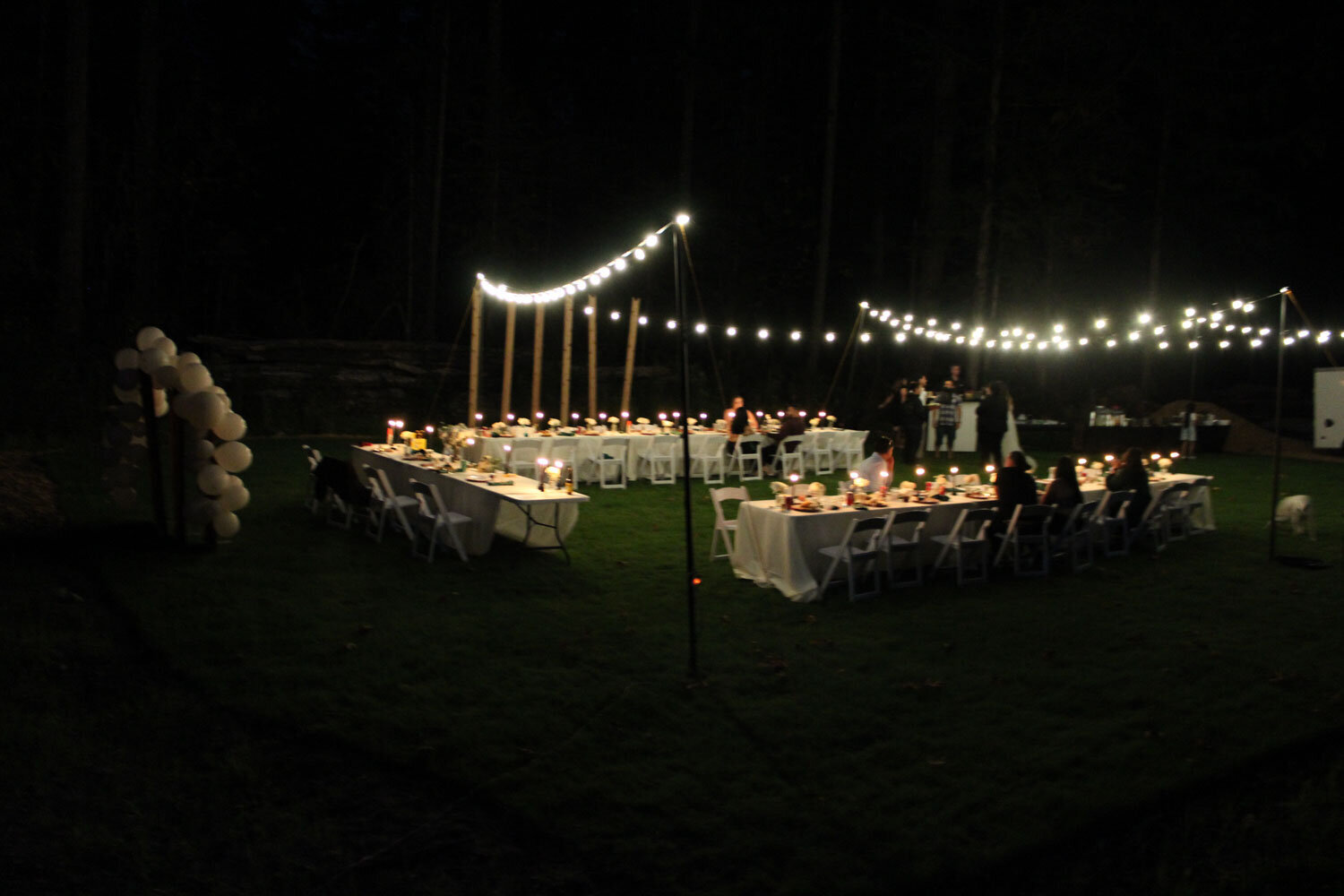 Nighttime outdoor wedding reception with tables and string lights