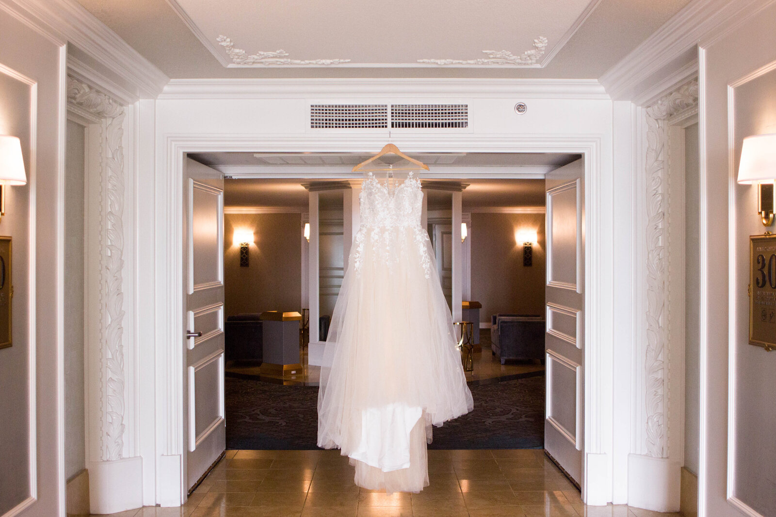 A lace wedding dress hanging in a doorframe.