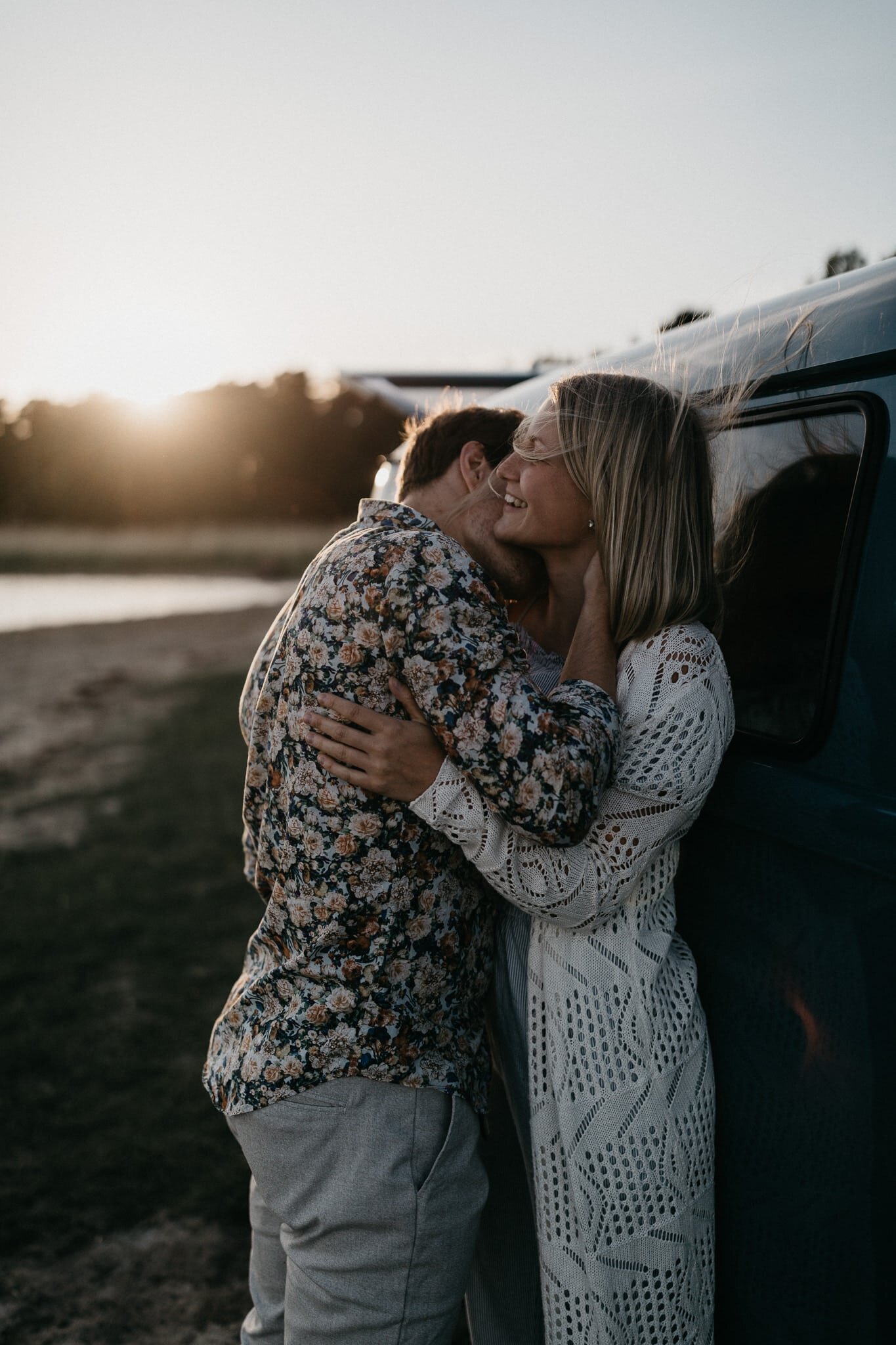 Couple hugging in sunset in front of old car