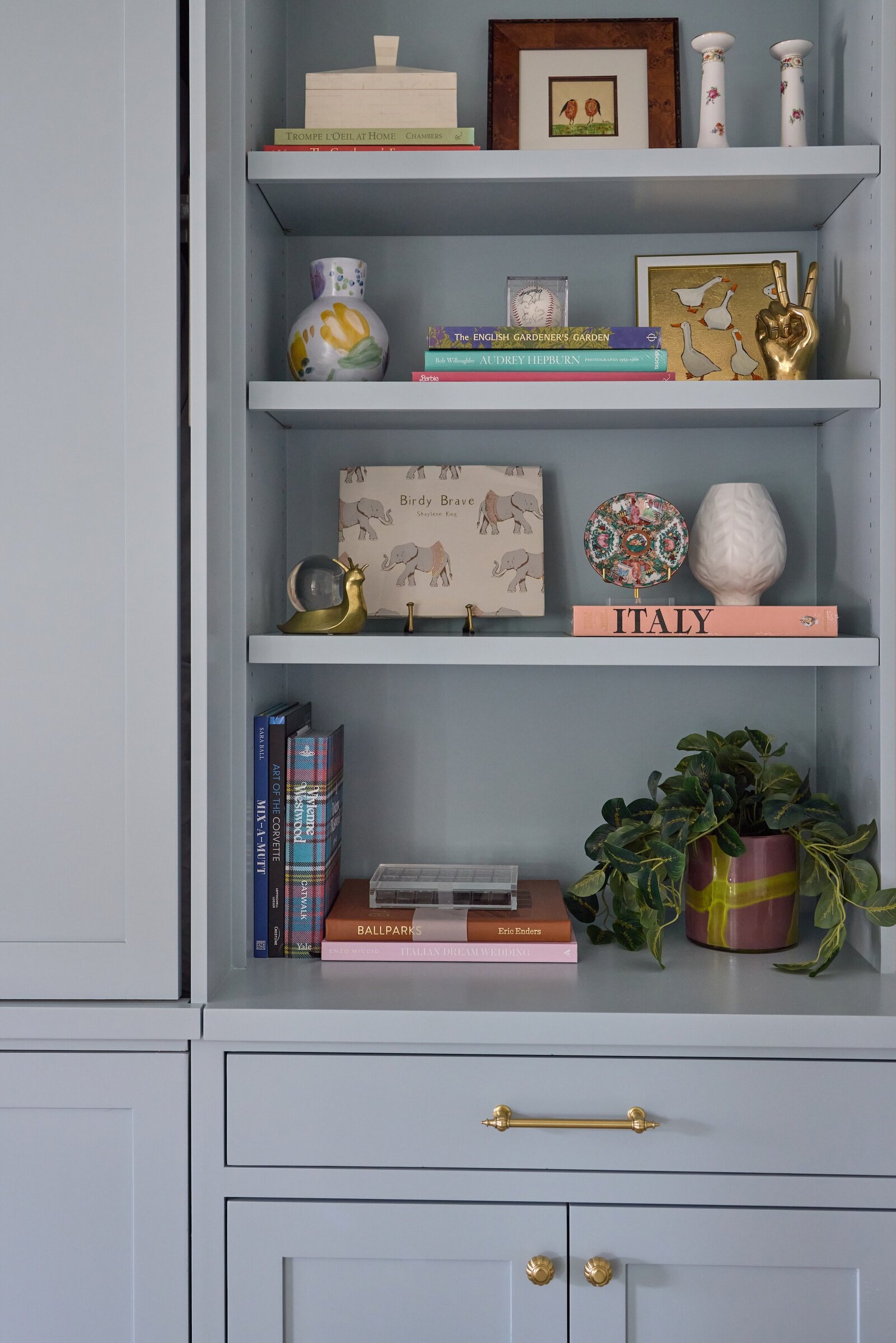 vision and hammer styled blue shelf with pink book and wooden fram and greenery plant