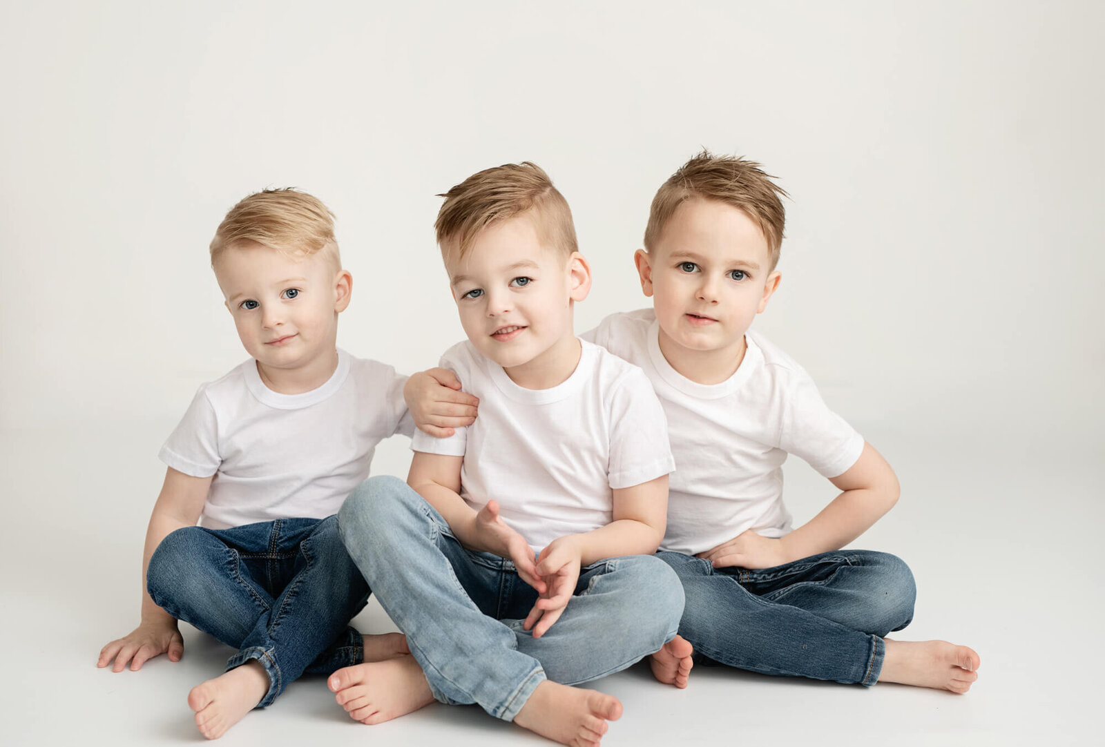 Sibling boys with blue jeans and white shirts and white background