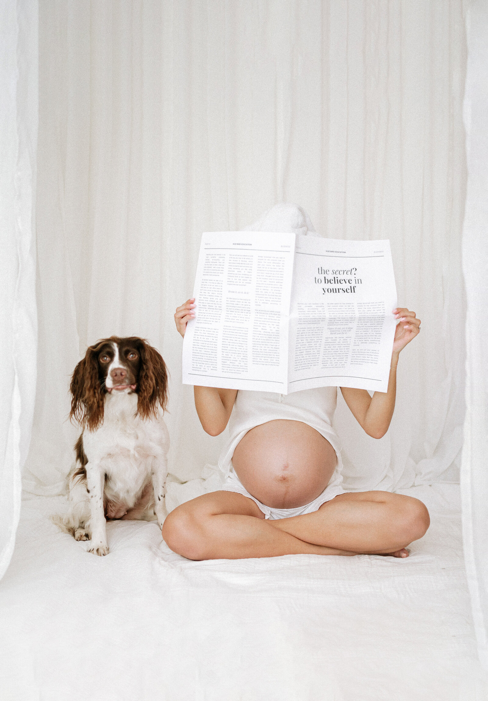 Maternity photography of a pregant woman reading a peper next to a dog