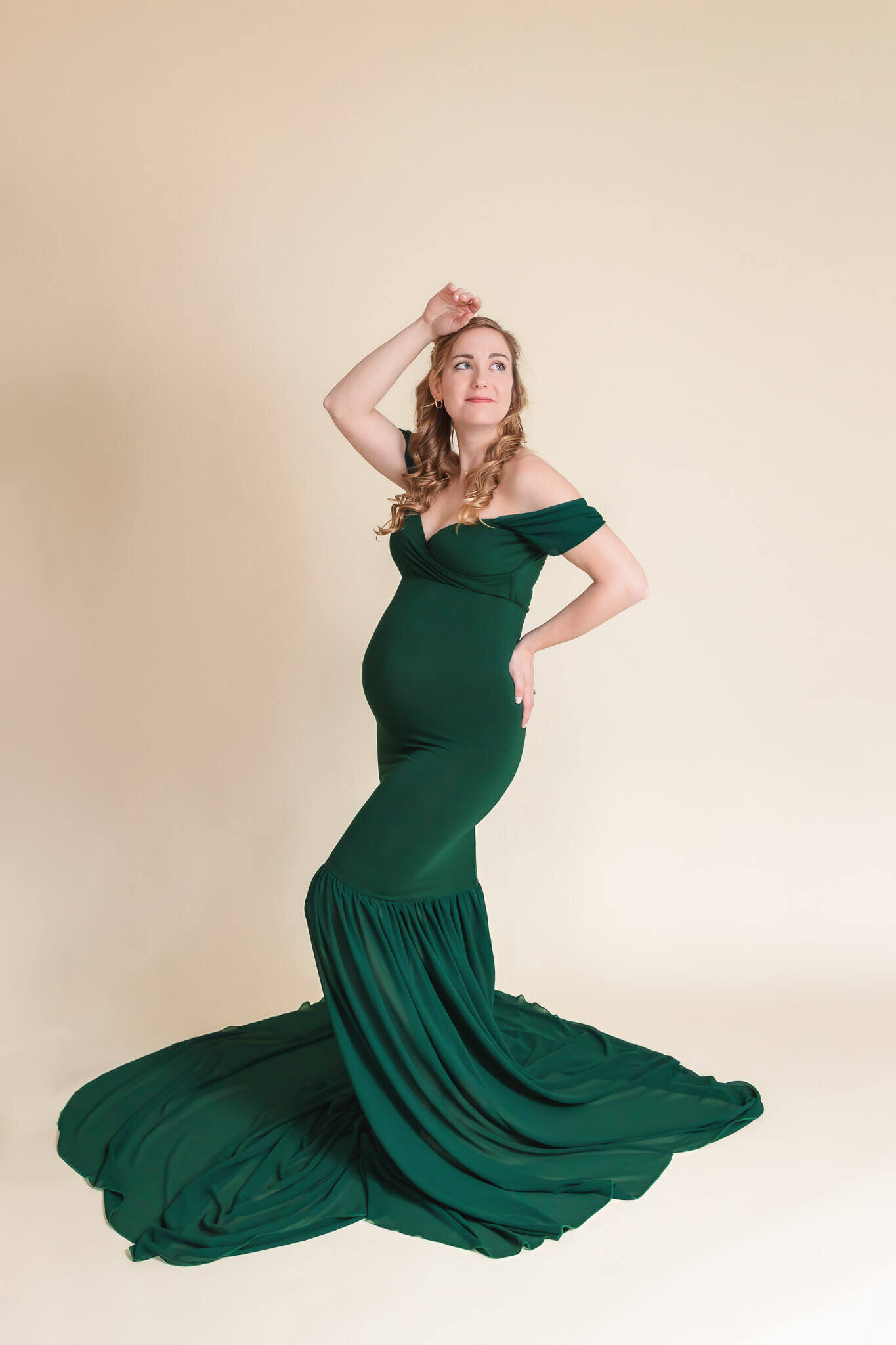A pregnant woman posing in a green dress.
