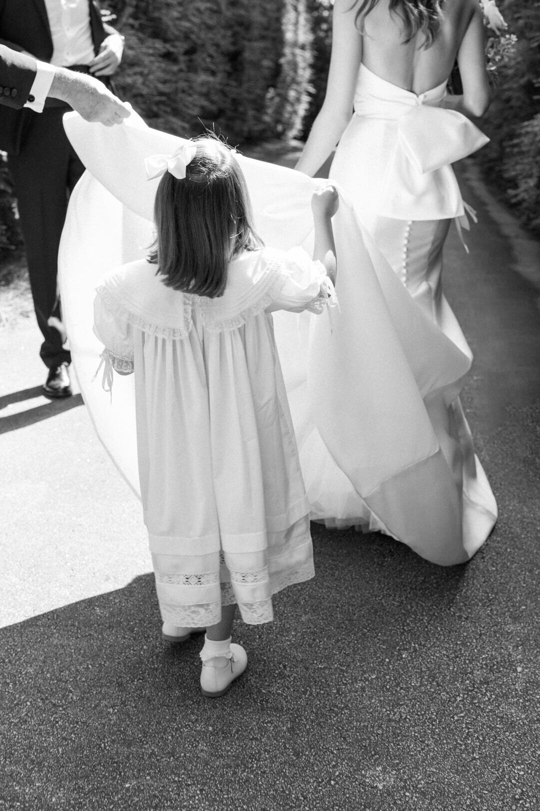 Black and white of flower girl holding brides dress