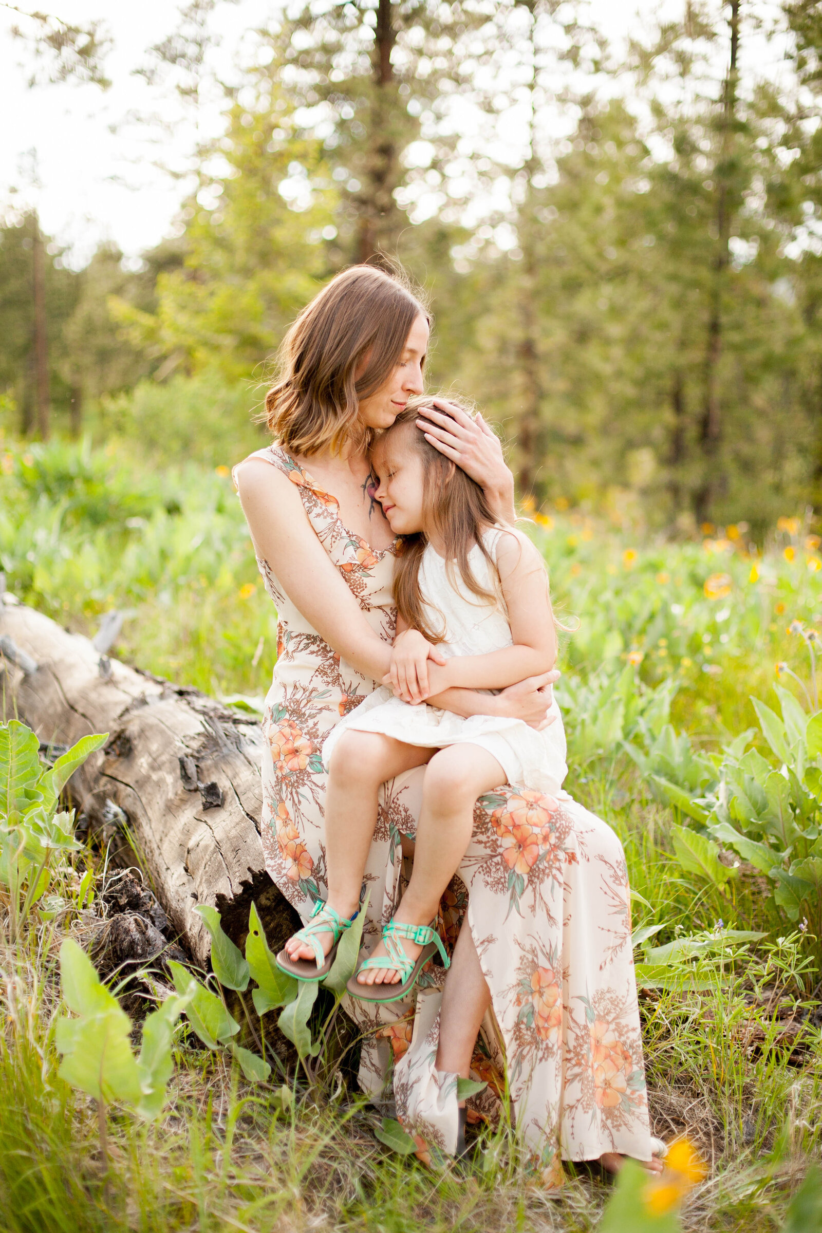 A brown haired woman holding her child in a field.