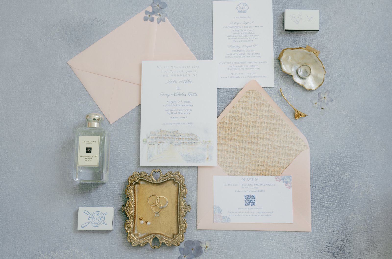 Elegant wedding flat lay with invitation suite, perfume, matches, and jewelery on linen backdrop