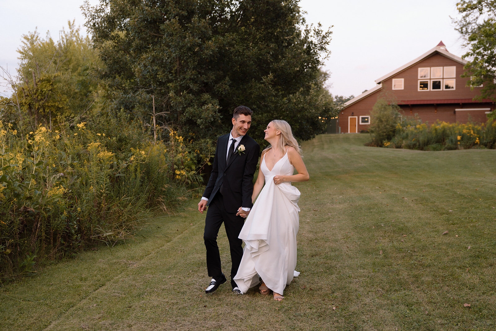 bride and groom laughing and sharing sweet gesture at the outdoor wedding venue at barnwood events in madison, winconsin