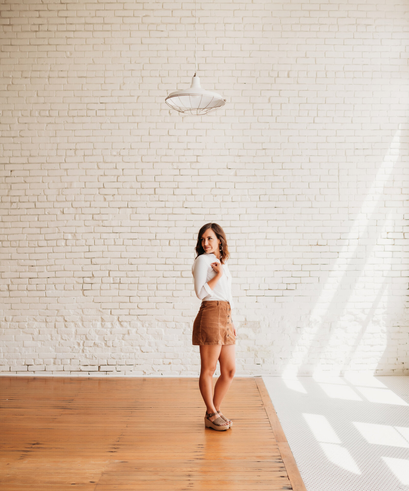 Branding Photographer, a woman stands in an open, empty, and well lit dance studio