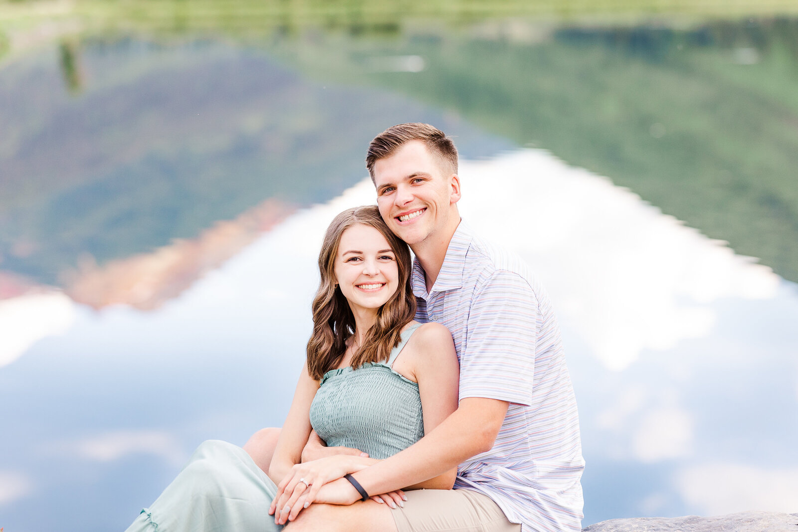newlyweds sit in front of lake