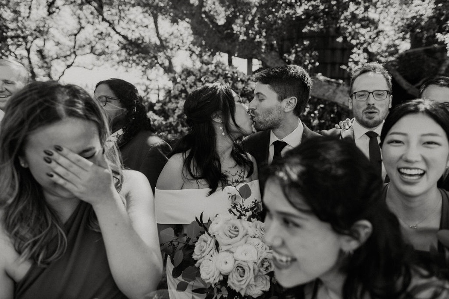 Bride and groom kissing surrounded by wedding guests