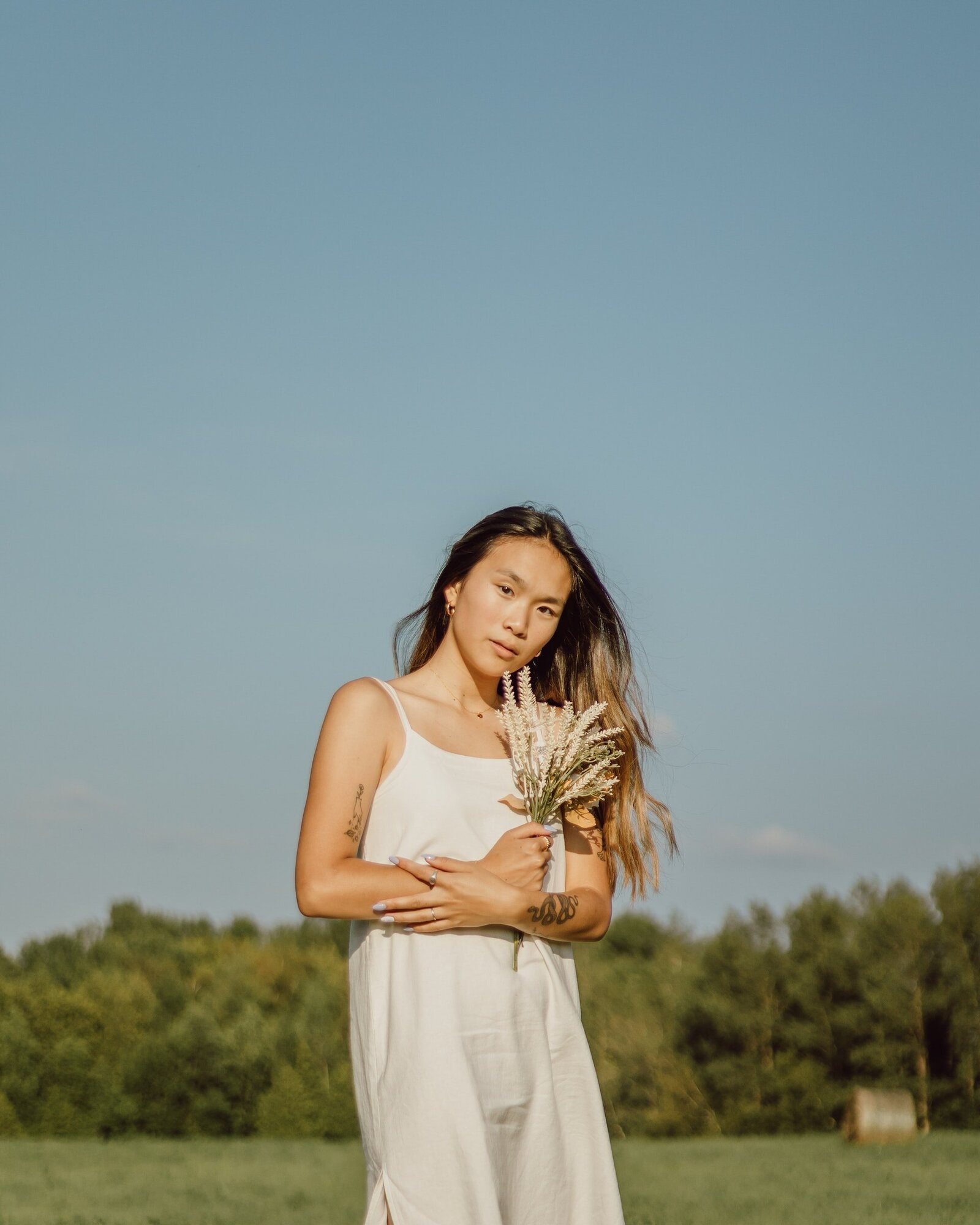 woman-in-white-spaghetti-strap-dress-holding-flowers