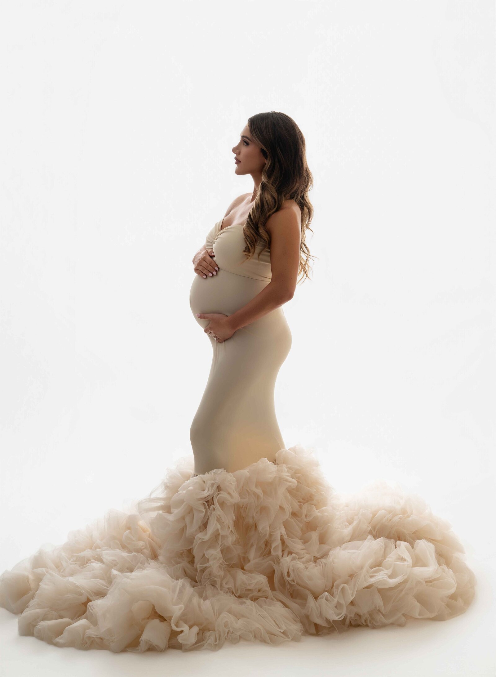 pregnant women wearing a mermaid fitted maternity gown with big tulle ruffles at the bottom. Photographed at Atlanta Maternity photo studio.