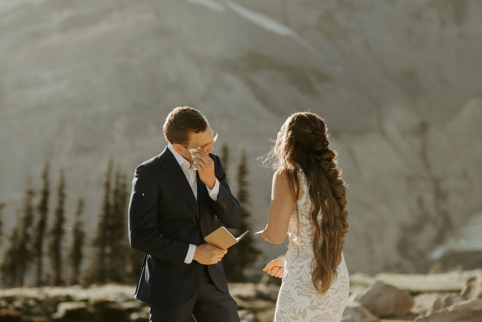 Groom wiping his tears in front of his bride while they read their private vows to each other in Mount Rainier National Park