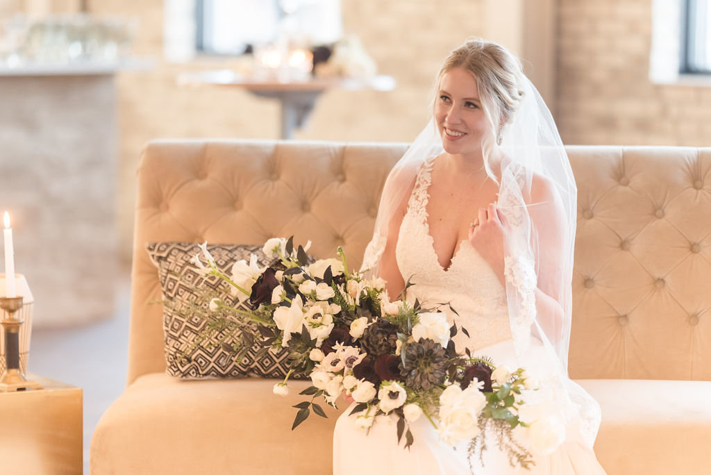 Bride sitting on a couch with a large bouquet