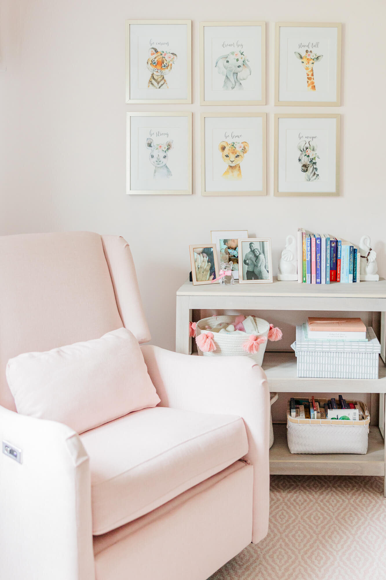 Nursery featuring a pink recliner, a bookshelf, and animal pictures on the wall