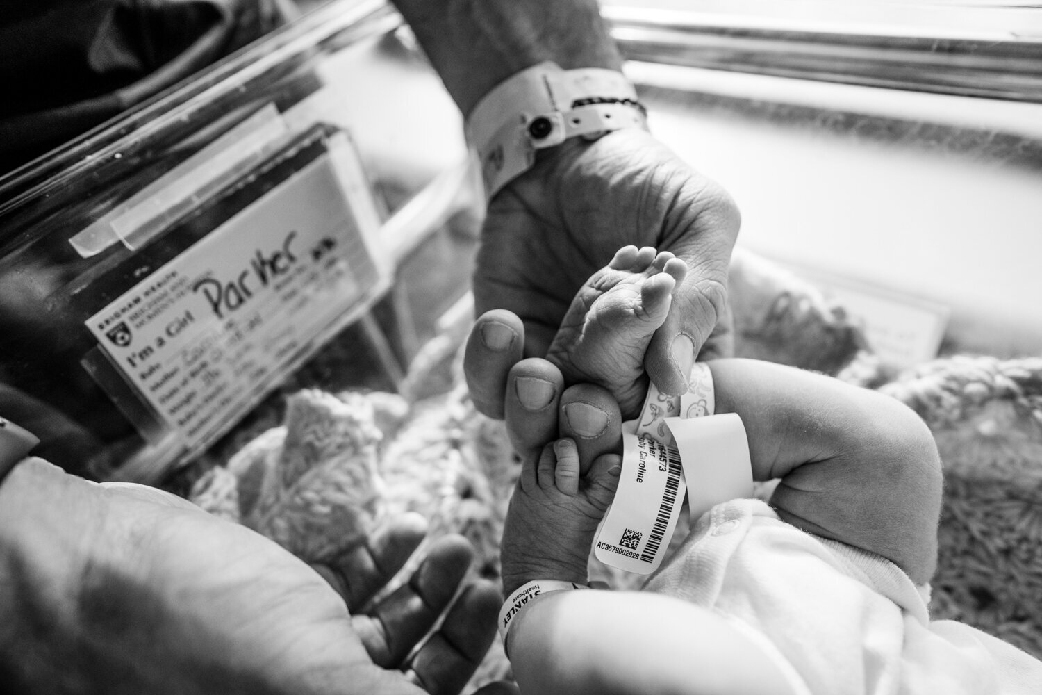 baby with hospital bracelets on ankles is held by dad
