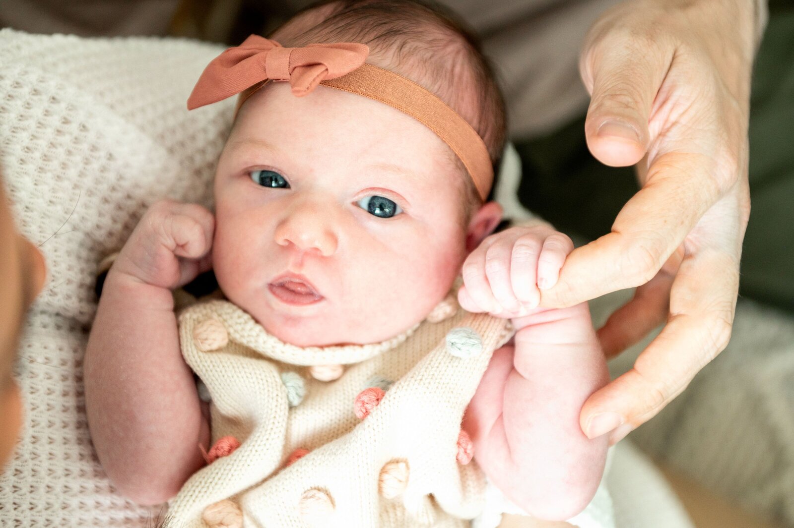 newborn girl holding her moms finger
