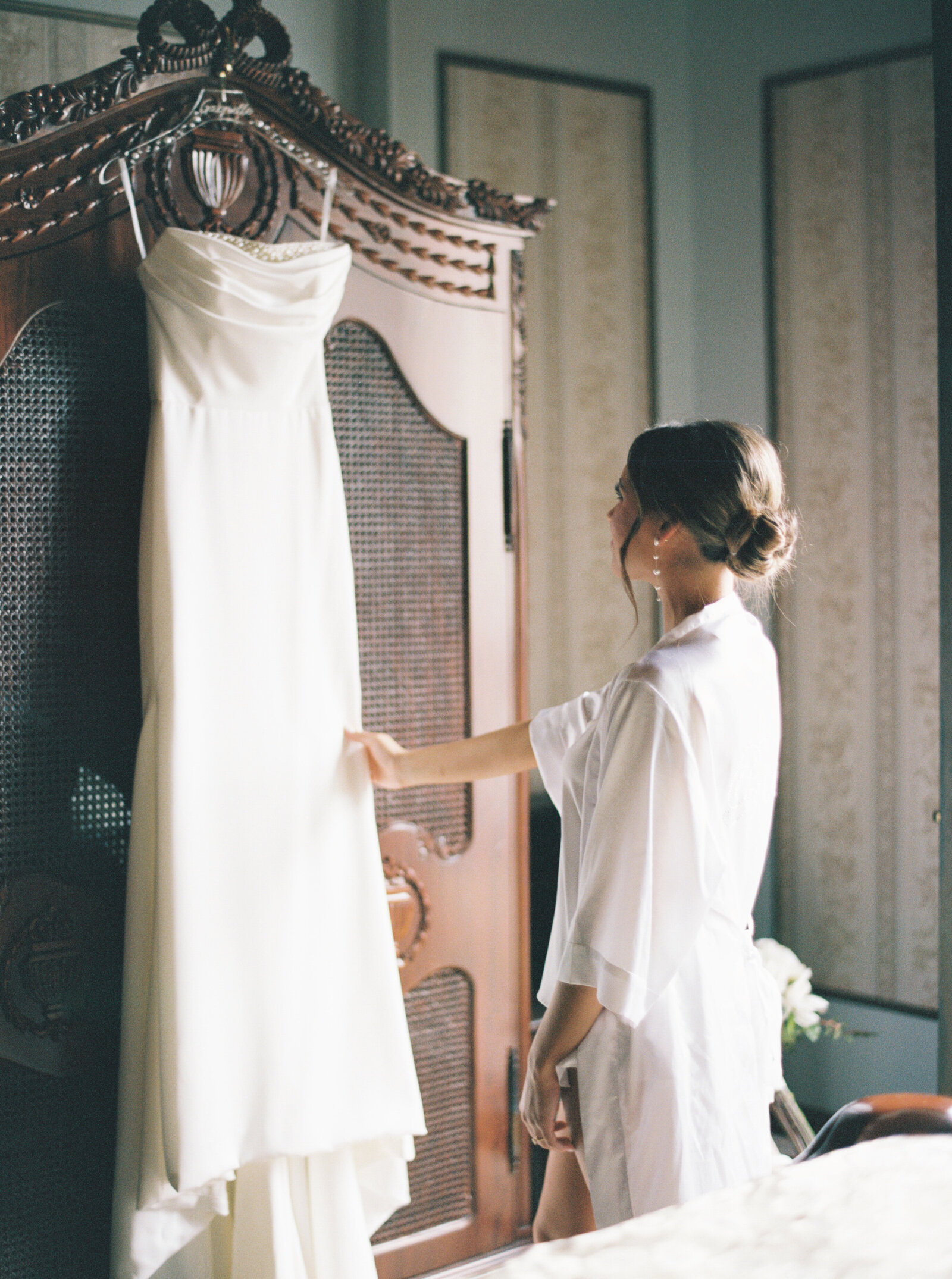 Bride lovingly admiring her wedding dress before the ceremony, captured on film by Morgan Alysse, Louisiana film photographer.