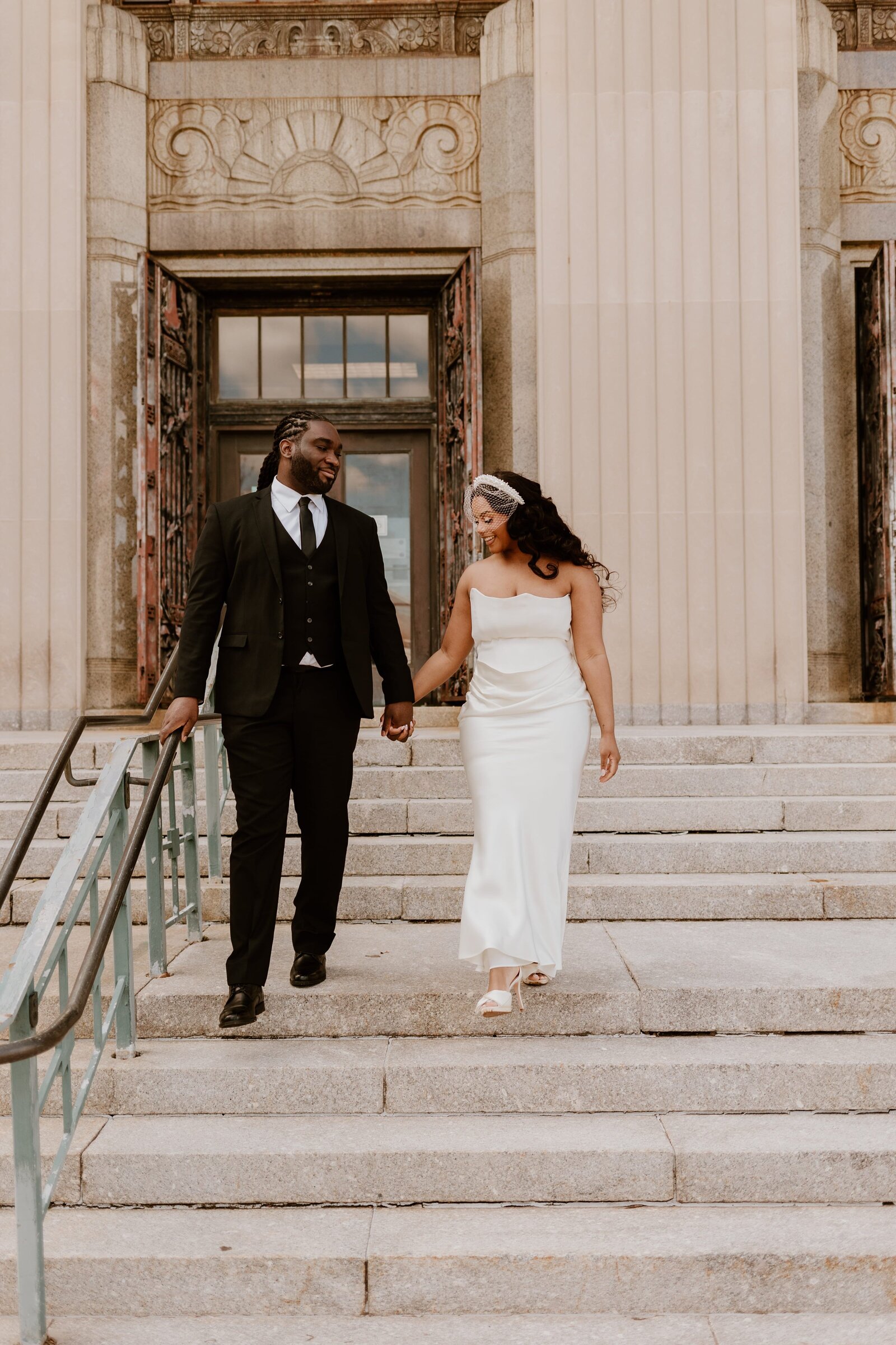 A couple walks hand in hand down the steps of a courthouse, captured by a Hudson Valley wedding photographer, exemplifying the grace and joy of their special day.