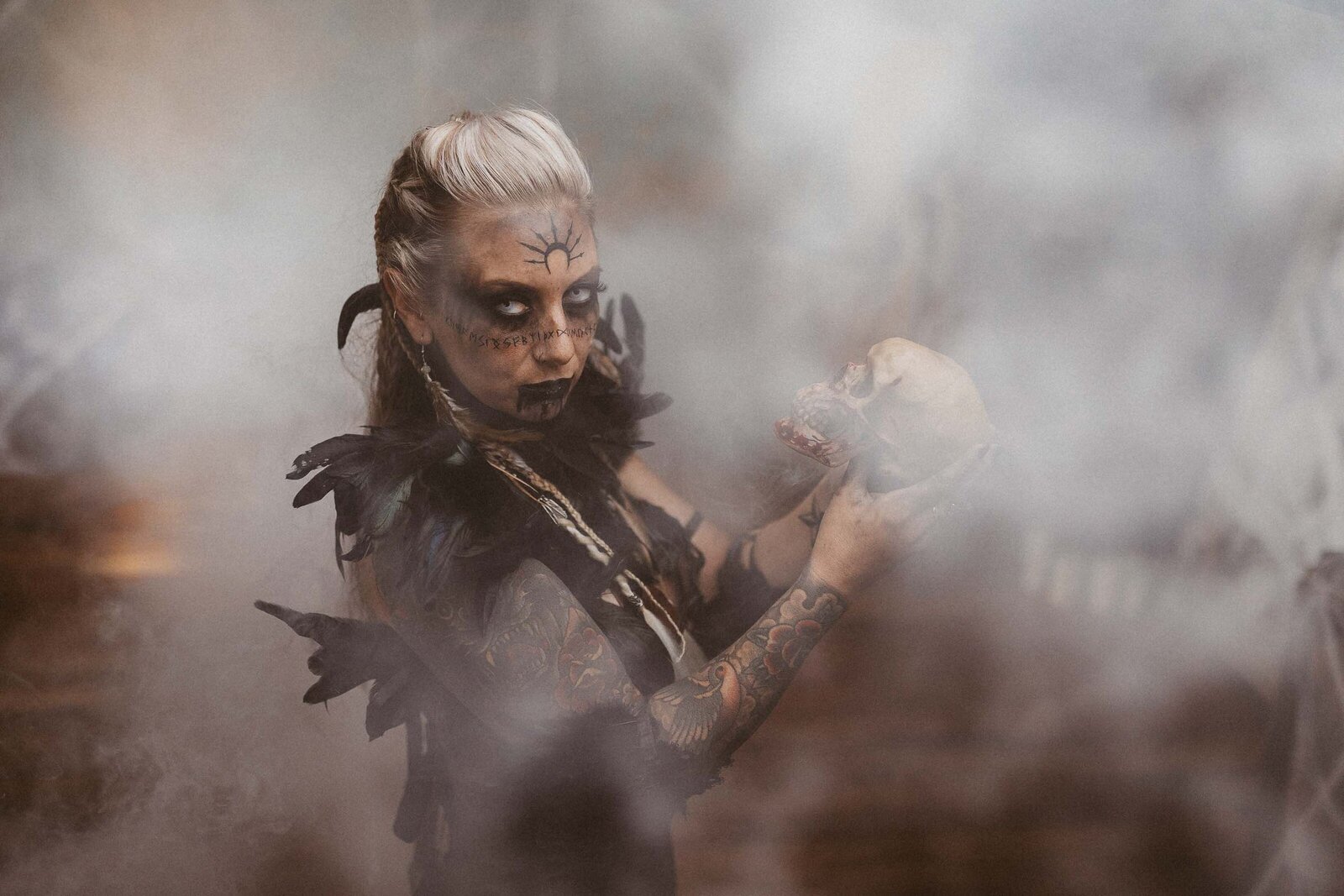 woman with spooky makeup holding a skull with smoke effect
