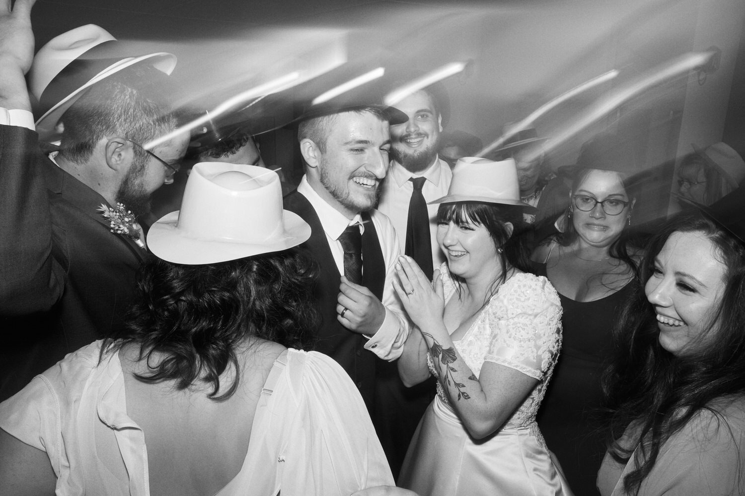 Bride and groom laugh on the dance floor surrounded by wedding guests