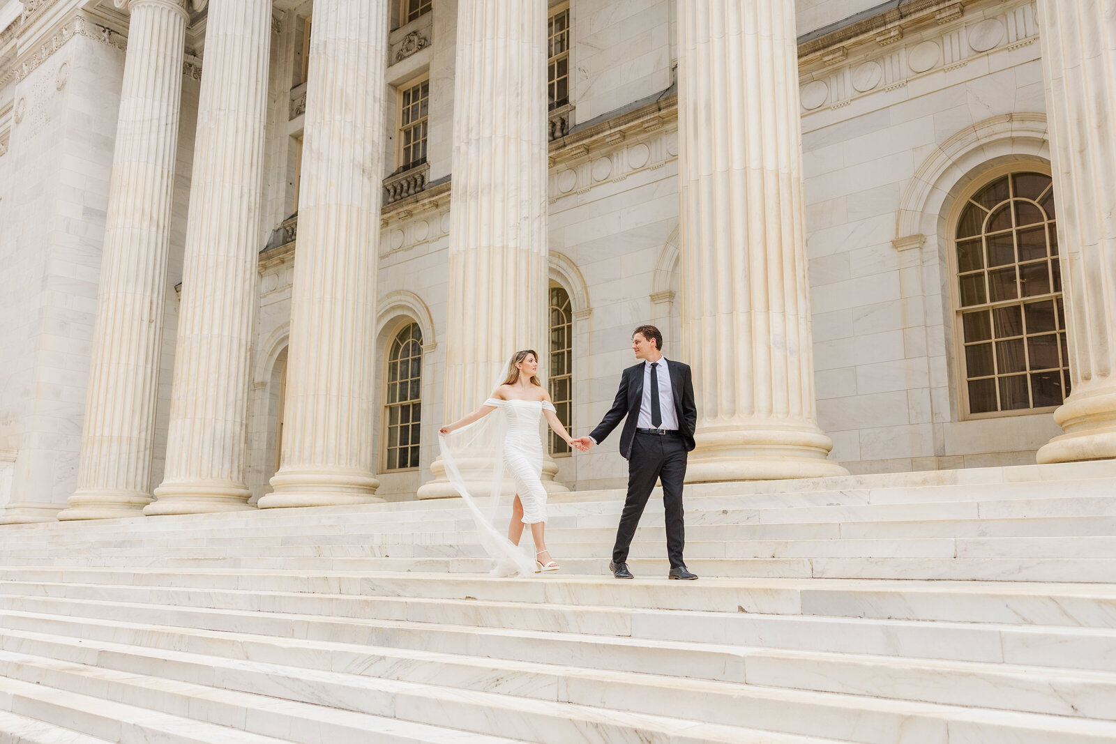 Bride and groom holding hands walking together at their courthouse elopement in Denver, Colorado at the Byron White Courthouse.