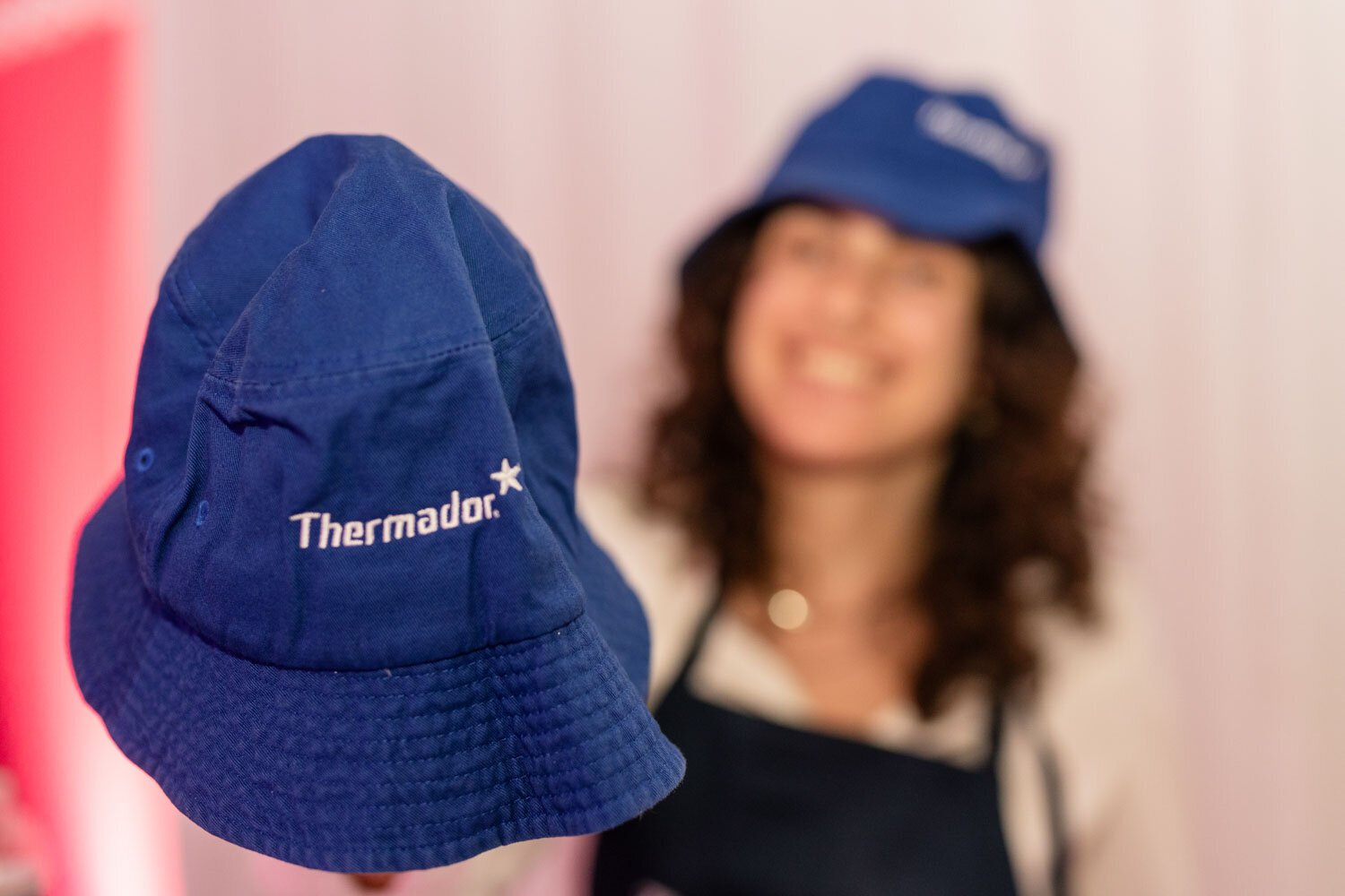 Close-up of a Thermador blue bucket hat with a smiling woman in the background