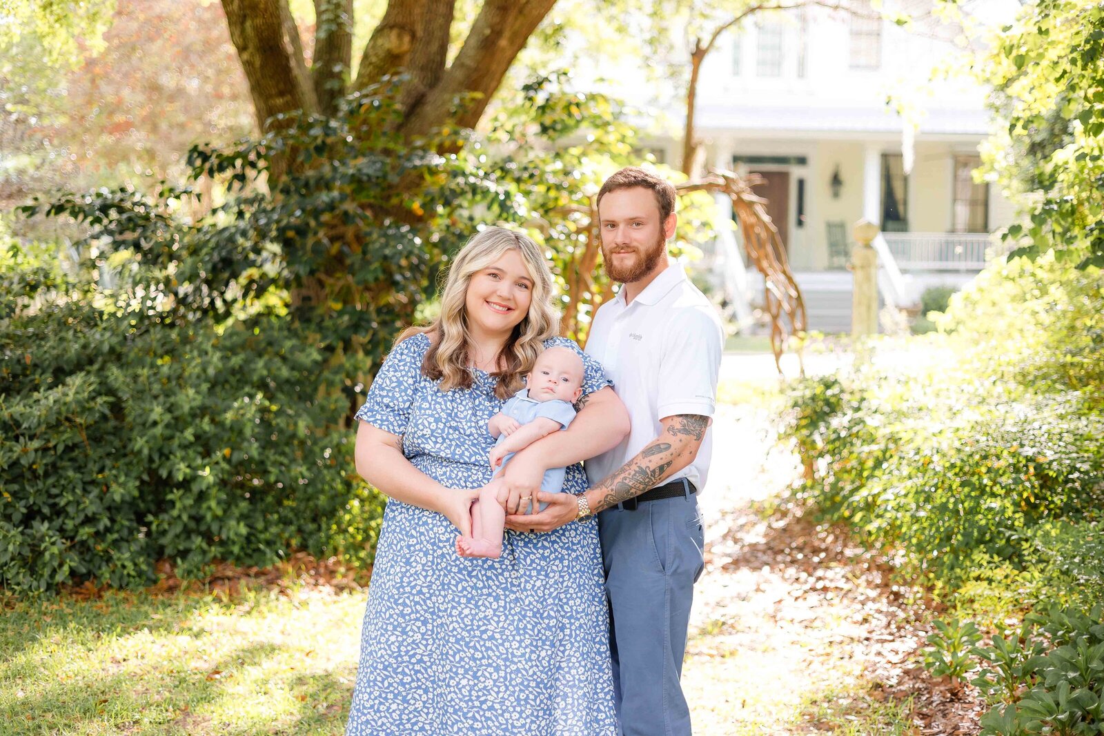 Mom and dad holding 3 month old boy all wearing blue and white at Woodlawn plantation and gardens in Guyton, Ga