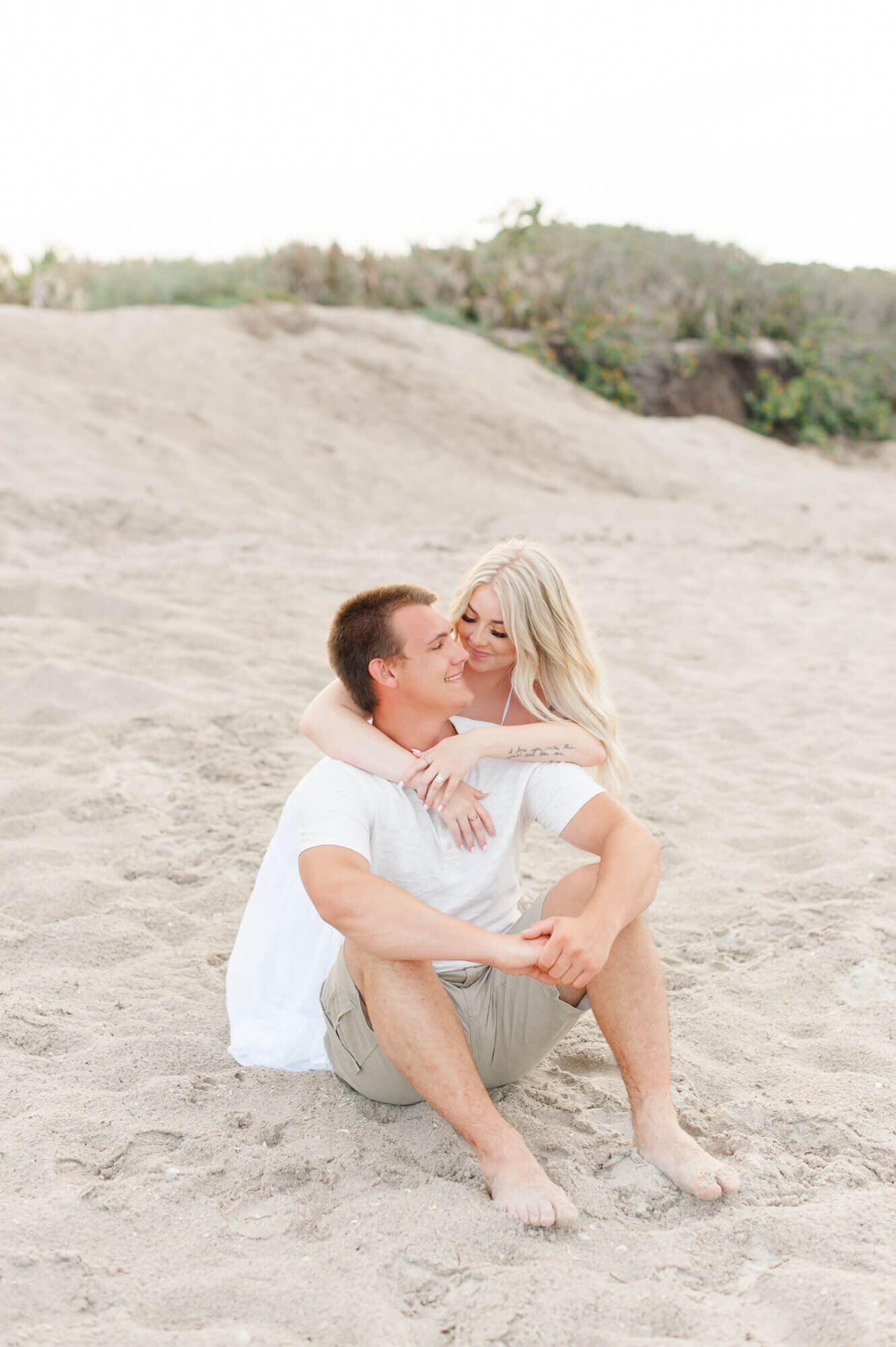 Photographer captures couple cuddling on the beach near the dunes east of Orlando