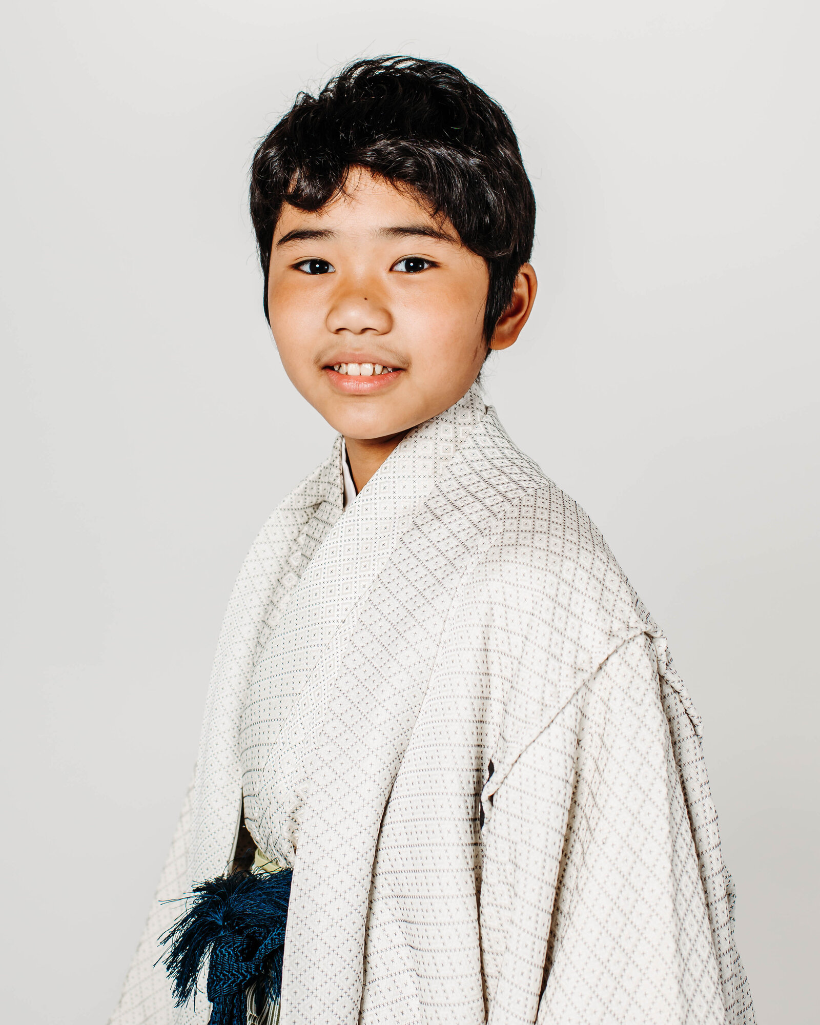 Young boy in white montsuki hakama smiling for a graduation portrait | 卒業式 白い紋付袴 男の子 ポートレート