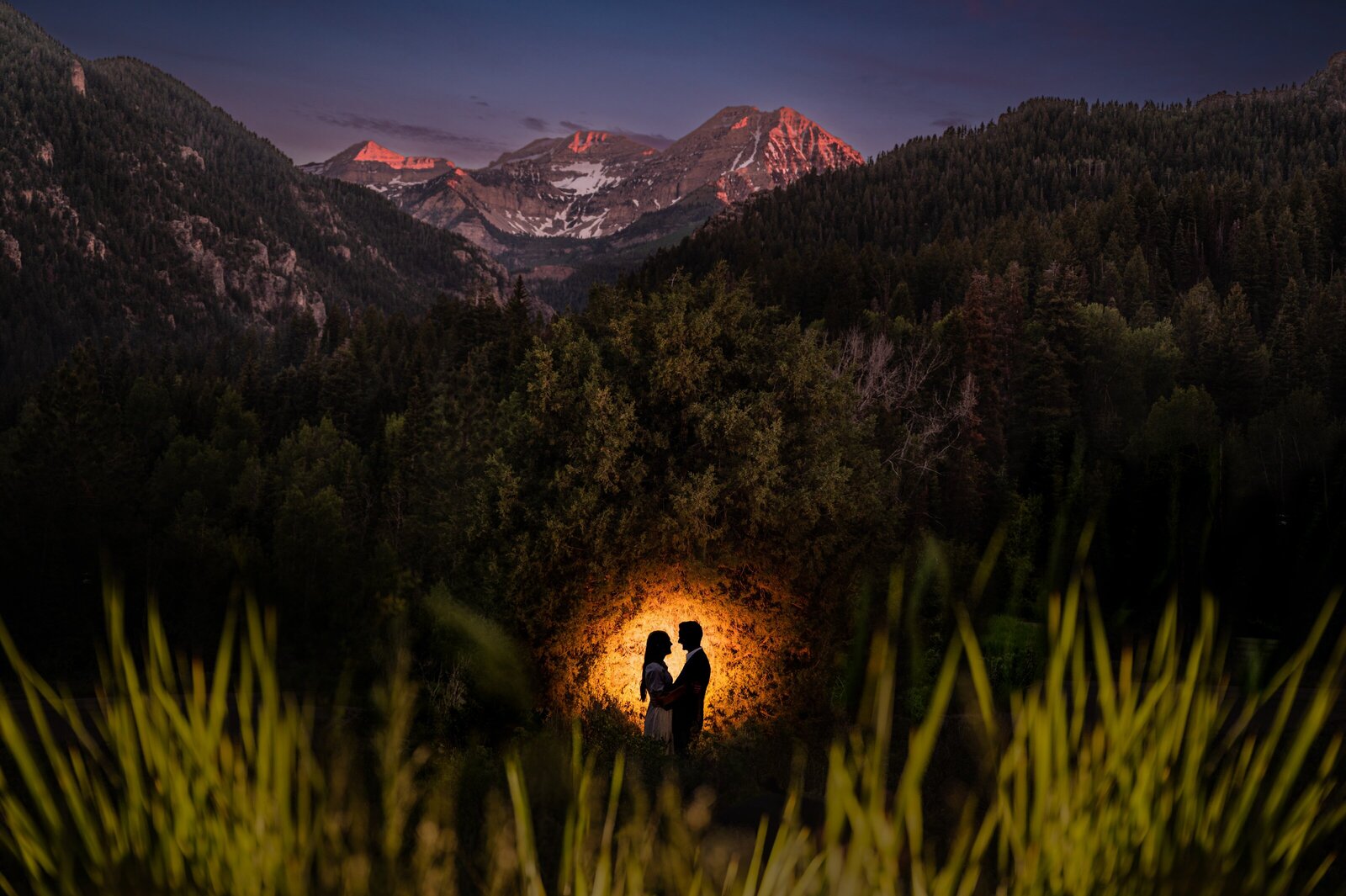 Couple silhouetted and standing underneath Mount Timpanogos in Utah during their engagement session
