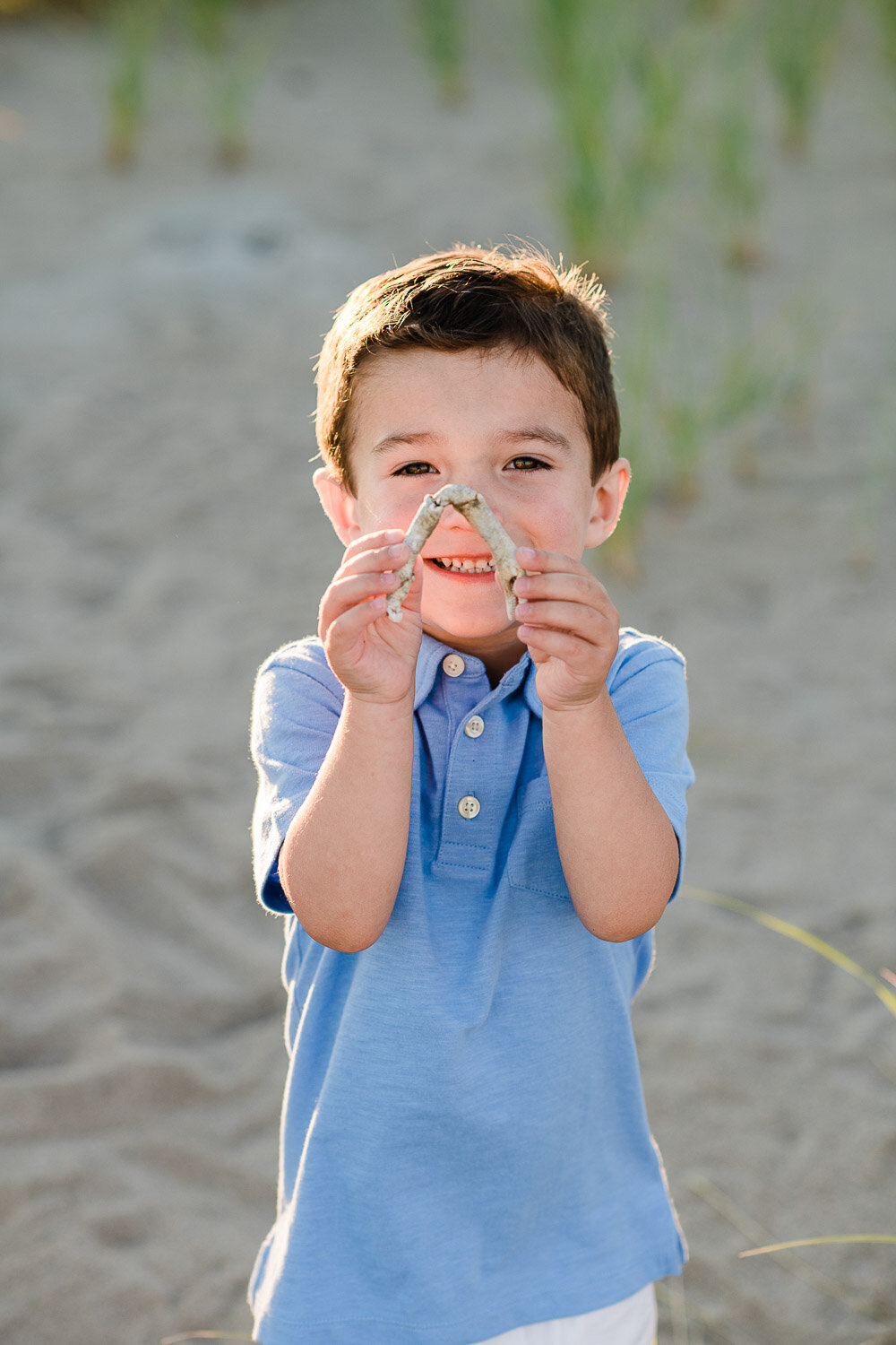 young boy with crab shell on beach