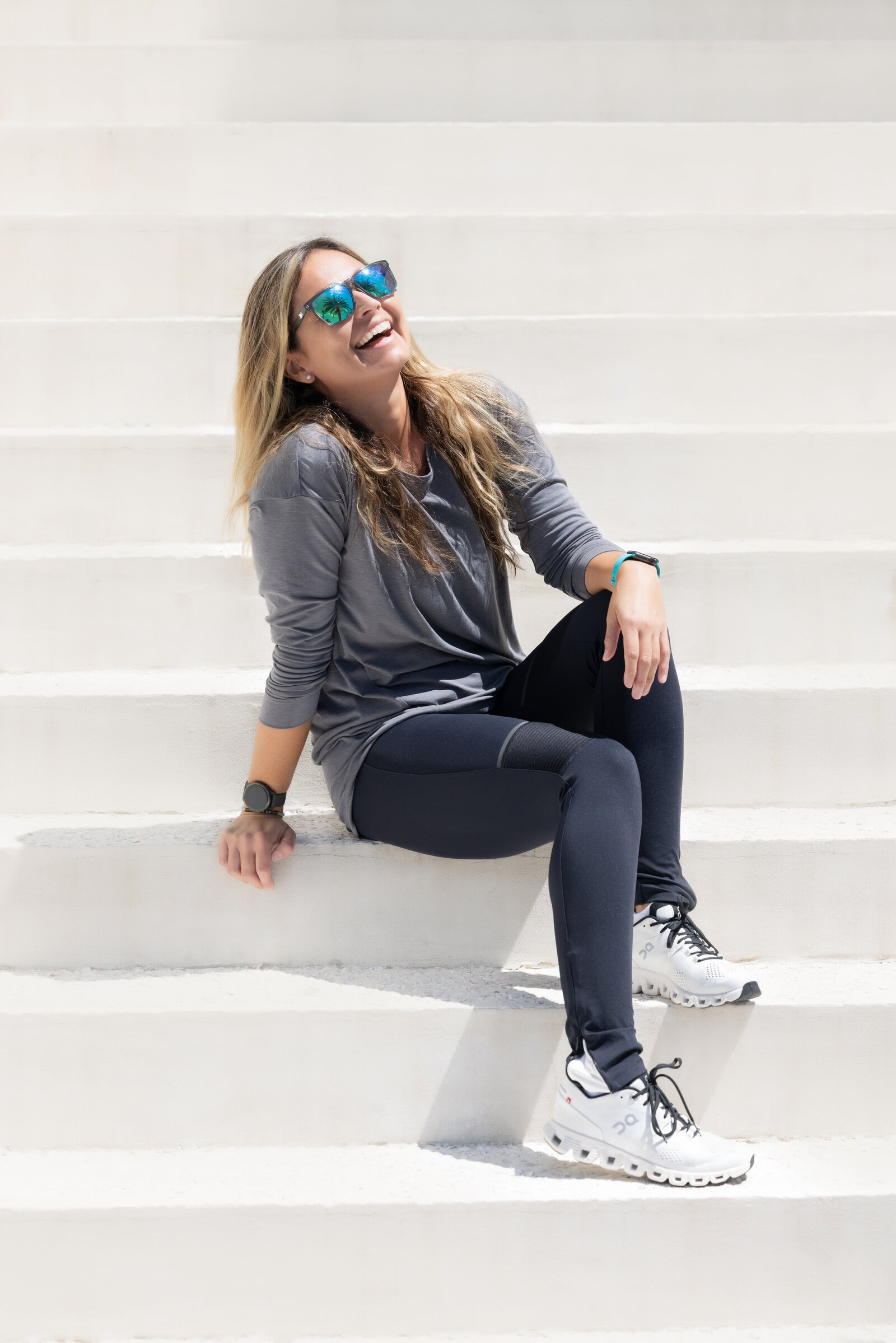 A woman laughing while sitting on a white staircase