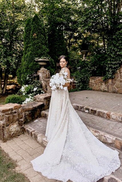 Lush greenery outdoor space with bride  showing off her wedding dress and bouquet at Stone Chapel at Mattlane Farm in Fayetteville, Arkansas